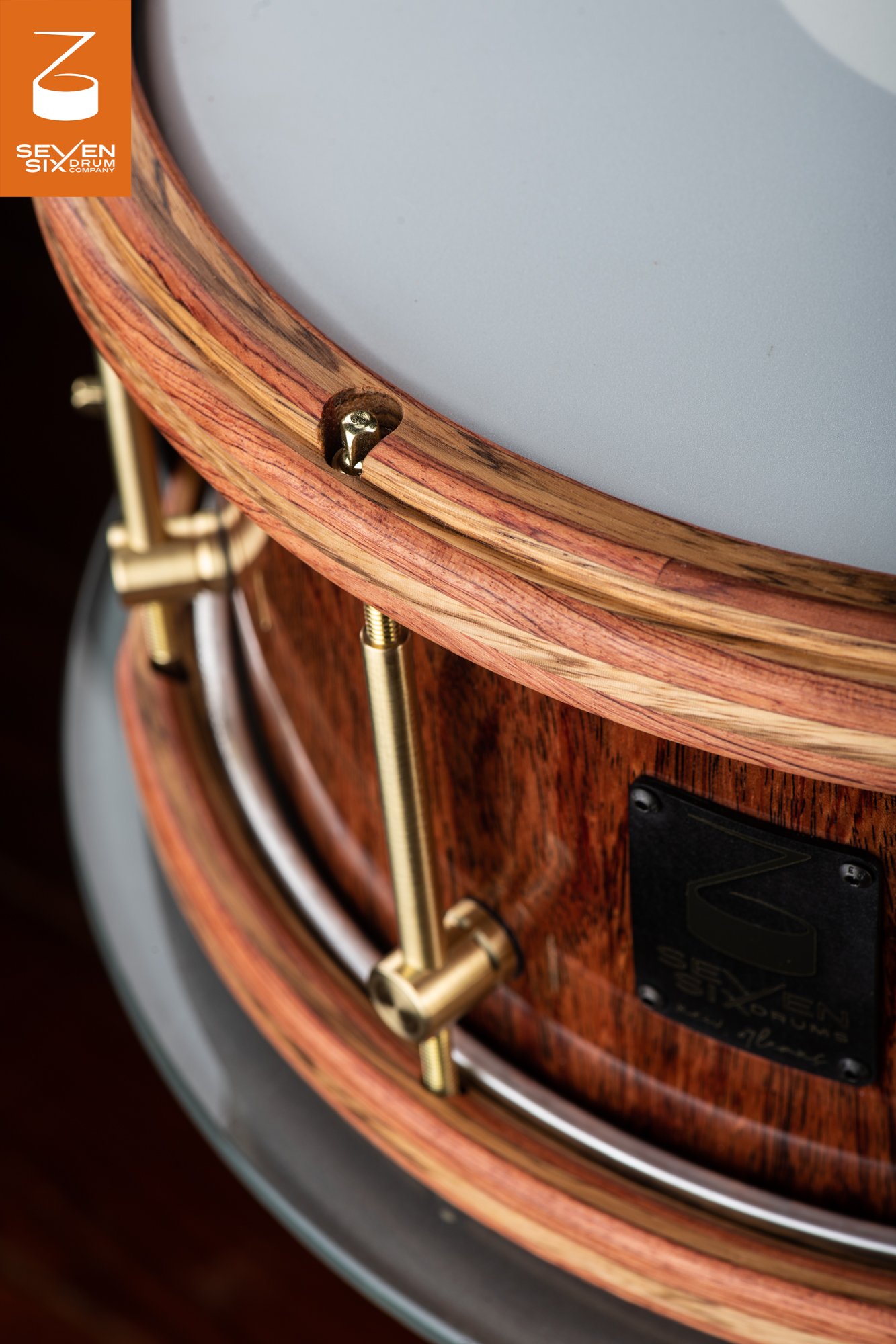 Handmade snare drum featuring a natural grain wood shell, matching laminated wooden hoops, and brushed brass hardware.