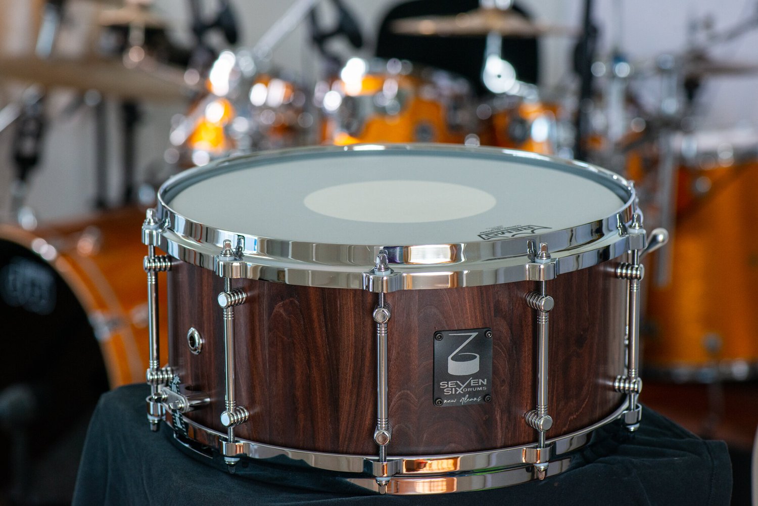 Handmade snare drum with a dark wood grain shell, satin finish, and polished chrome tube lugs and hoops.