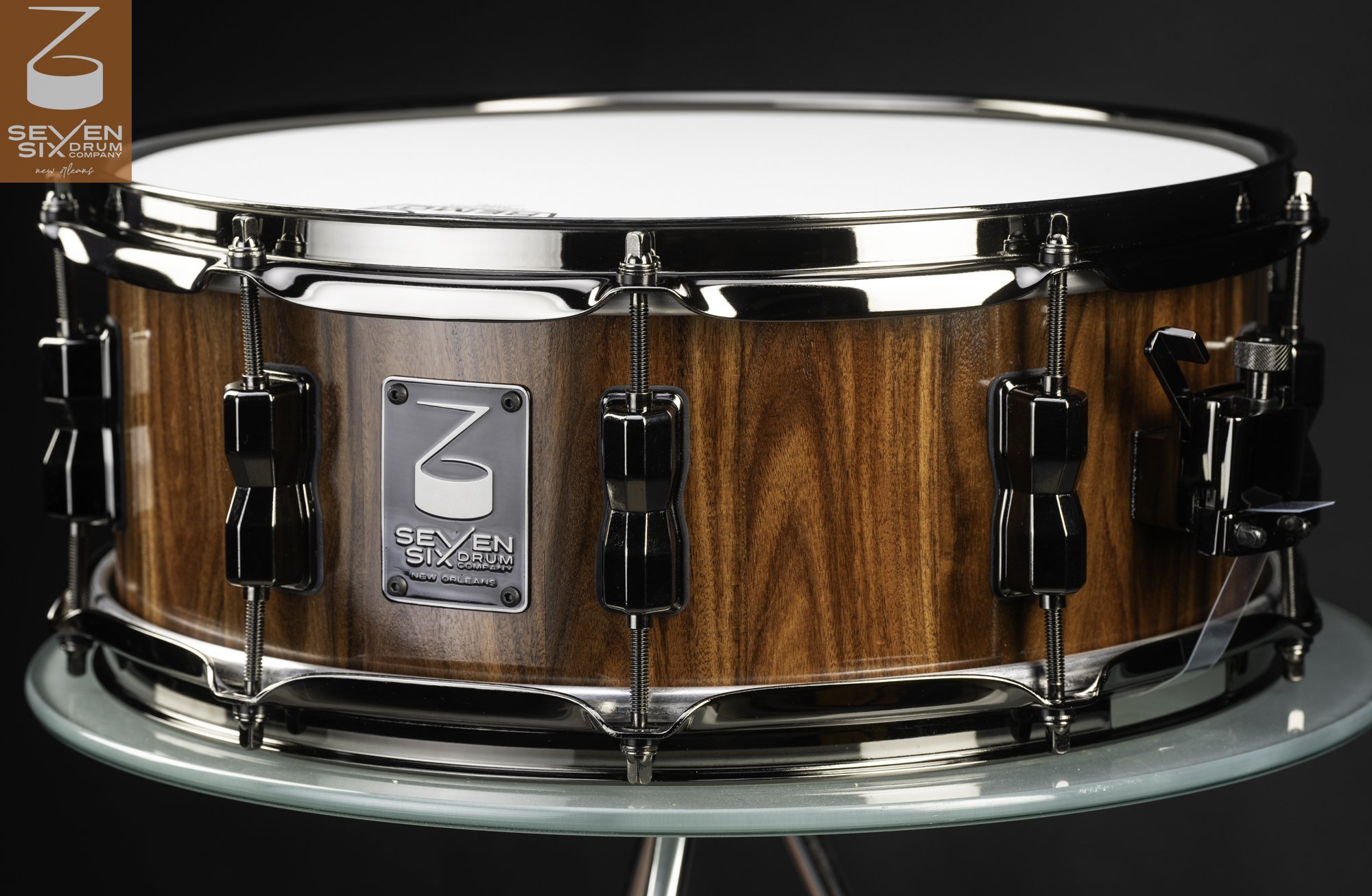 Handmade snare drum with a natural wood grain shell, finished with polished black nickel hoops, lugs, and hardware.