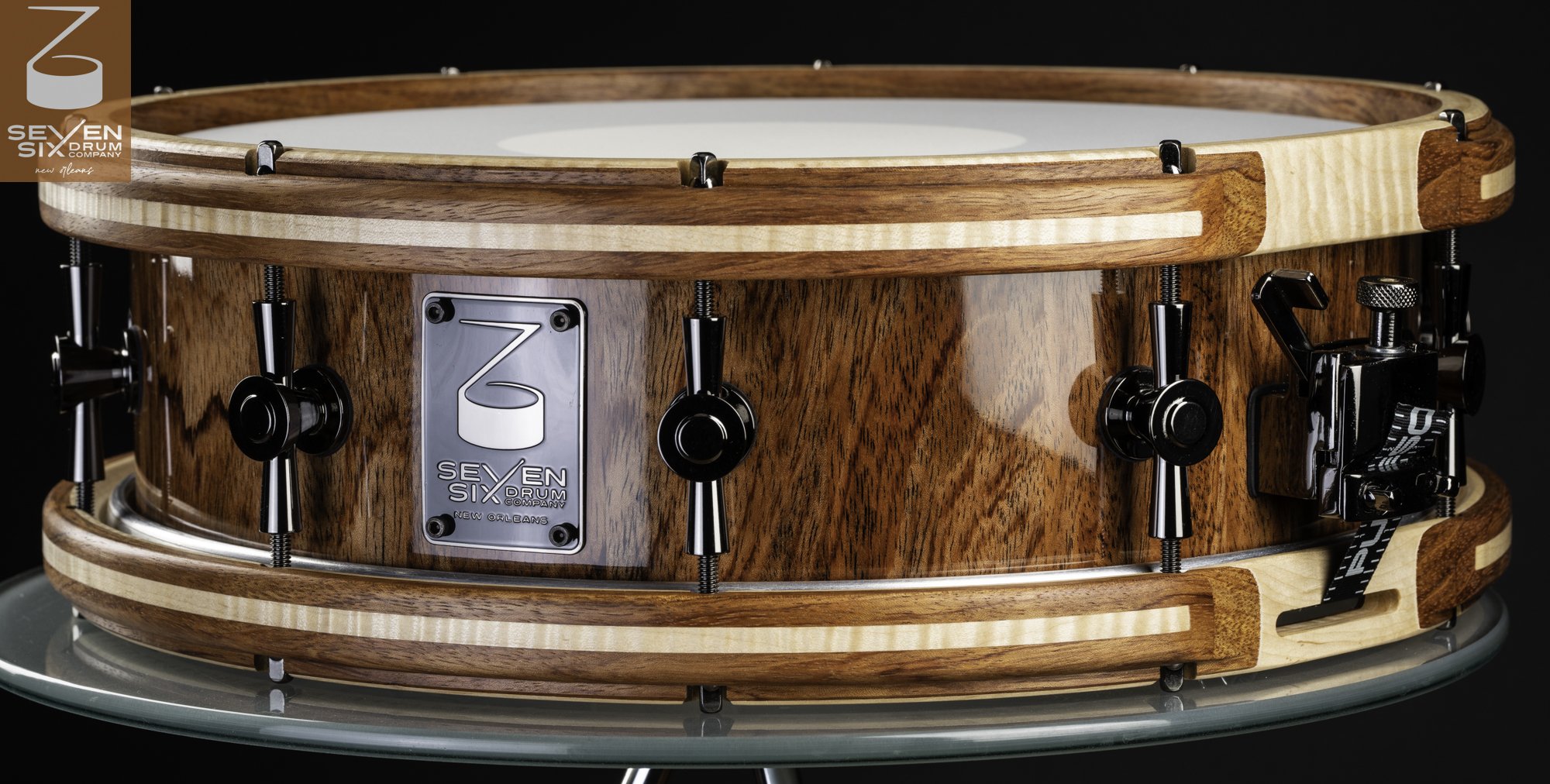 High-gloss wood snare drum with striped wooden hoops, black nickel lugs, and an adjustable throw-off.