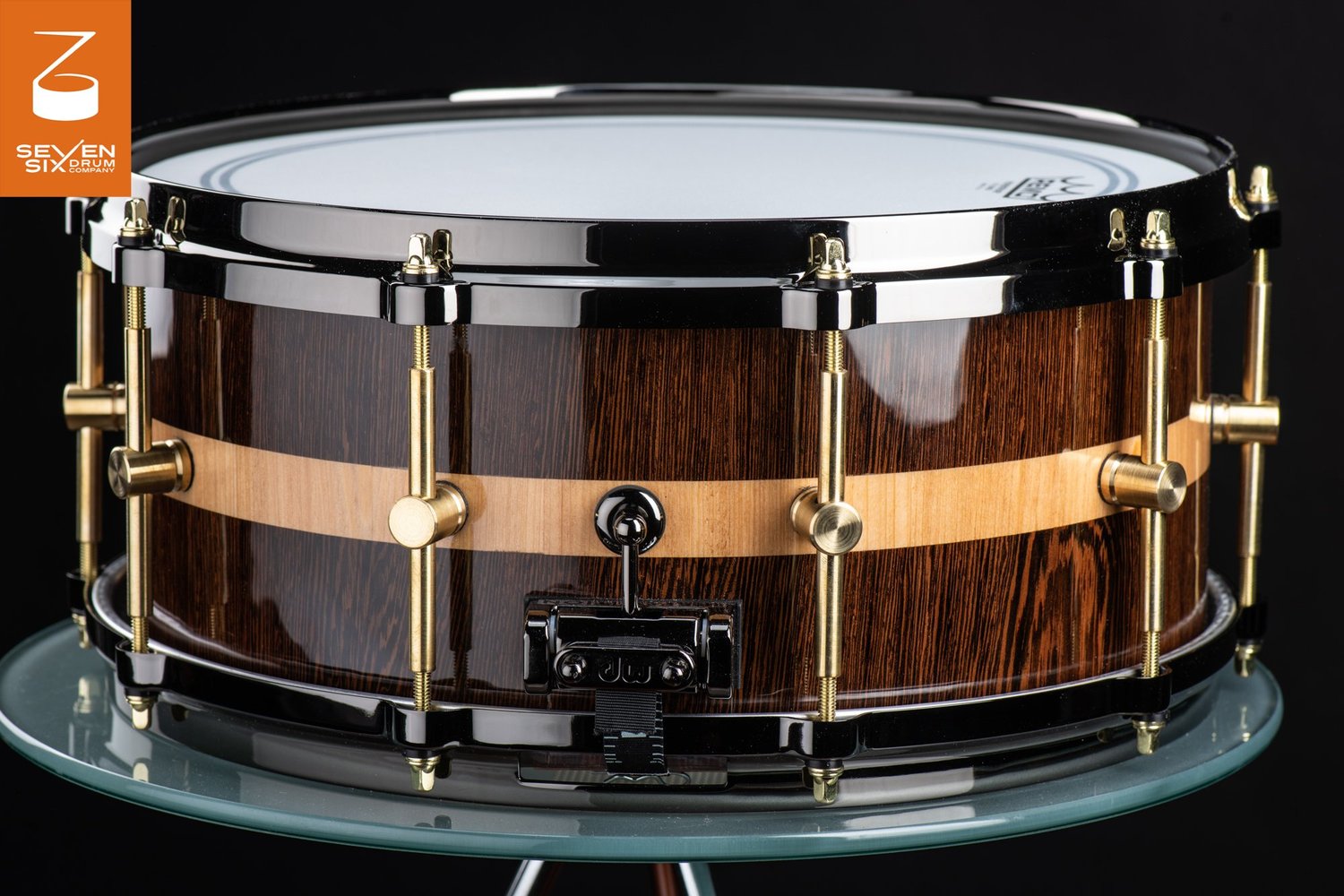 Gloss dark wood snare drum with a light wood stripe, brass single-post lugs, and black metal hoops.