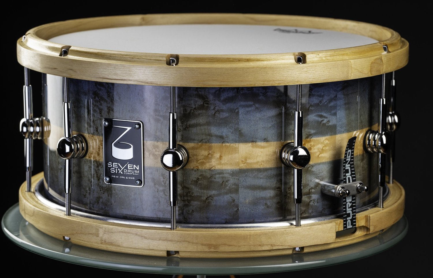 Handmade snare drum with a dark blue to aqua fade and natural birdseye maple shell, light wood hoops, and chrome single-point lugs.