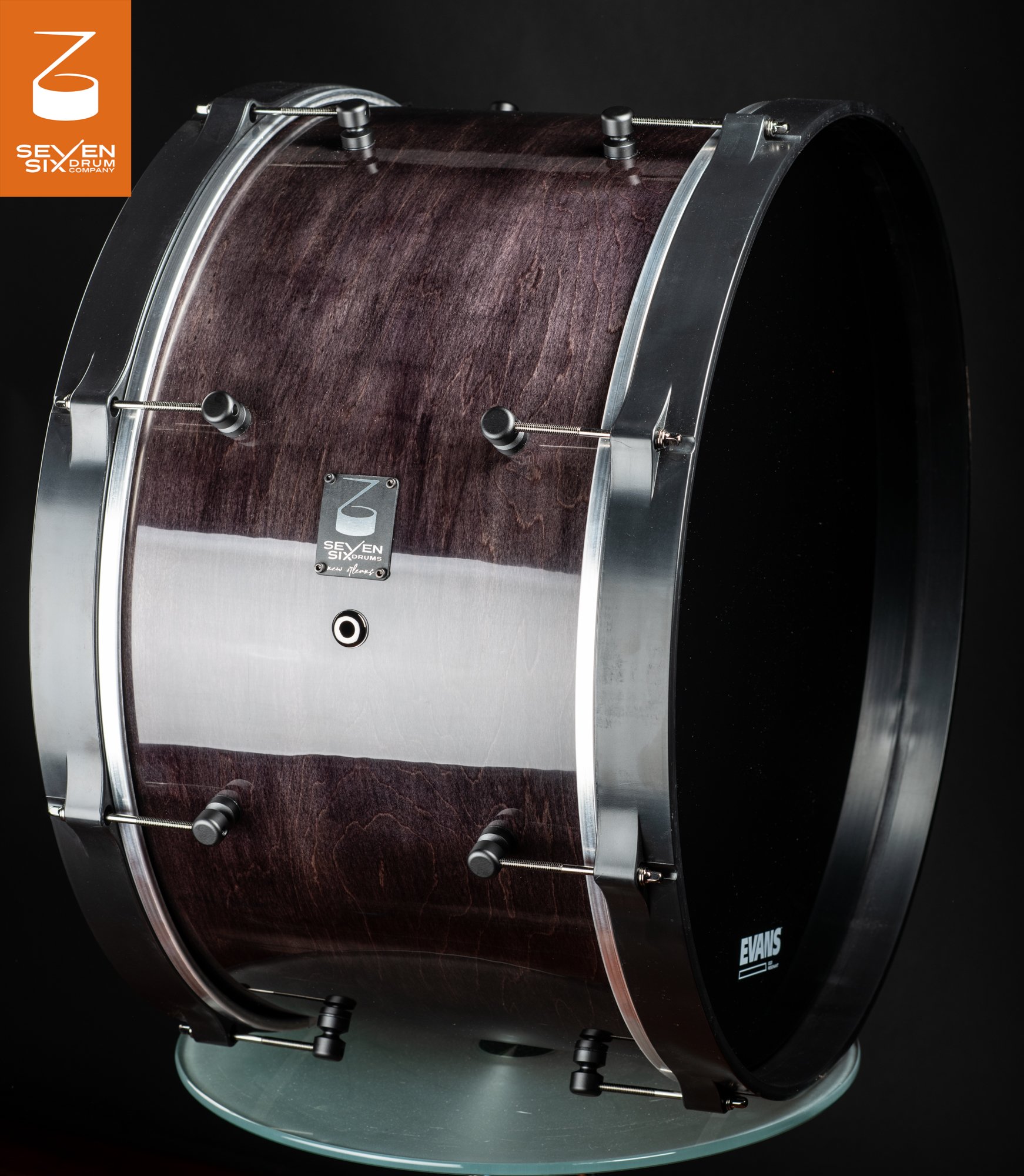 Glossy dark purple-stained wood bass drum with satin black hoops and minimalist black cylindrical lugs.