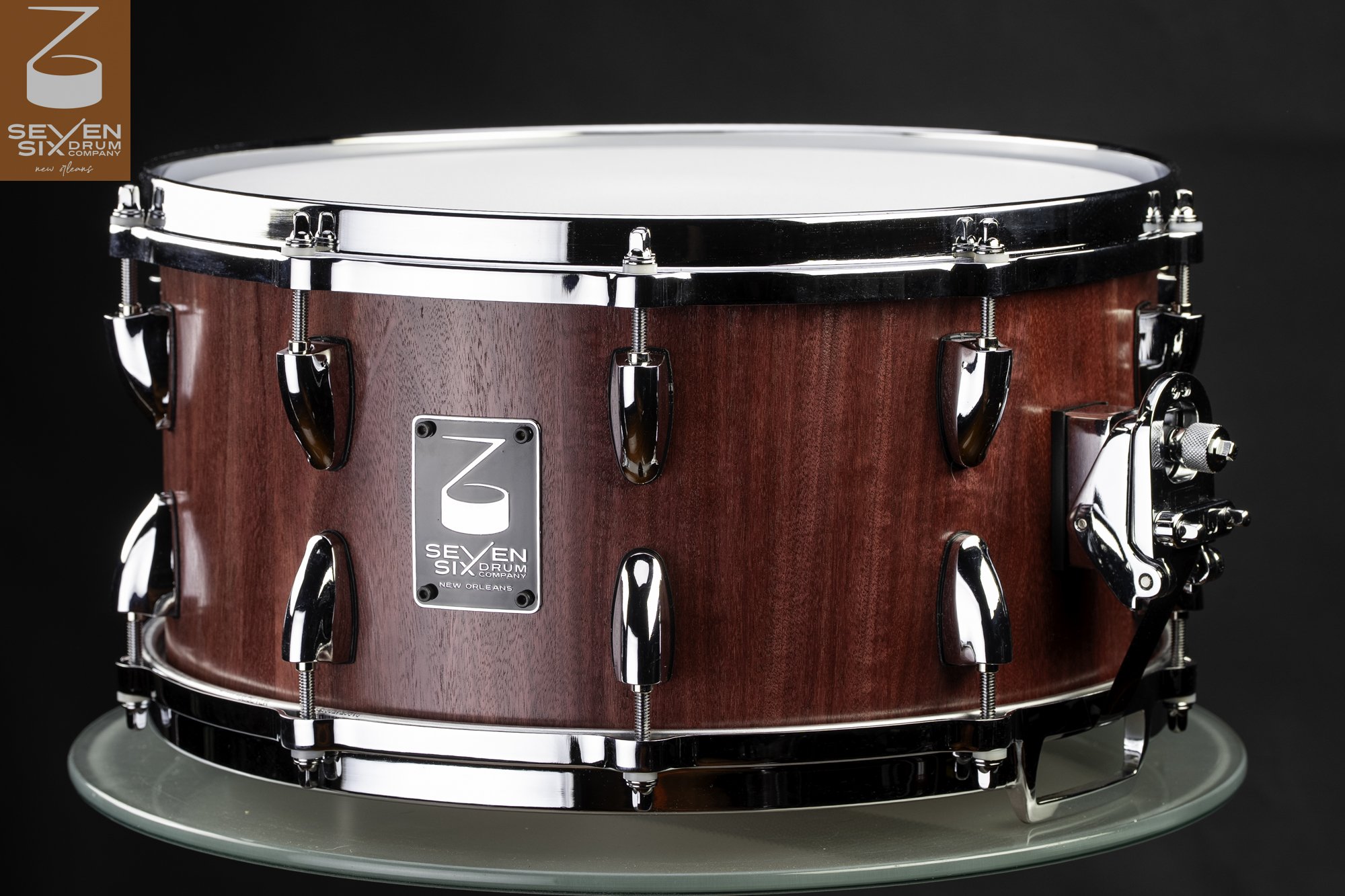 Handmade snare drum with a satin reddish purpleheart shell, dual rows of chrome lugs, polished hoops, and a chrome throw-off.