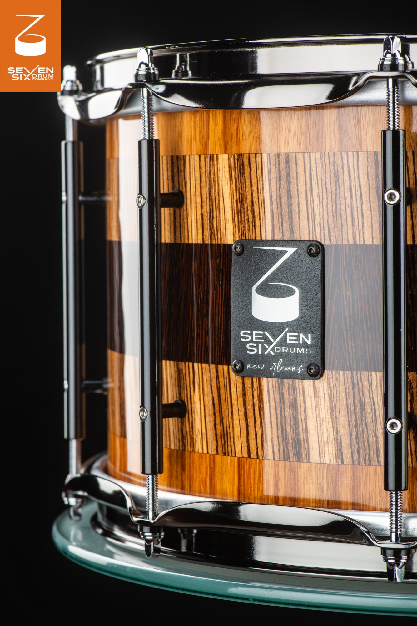 Handmade snare drum with a high-gloss zebrawood shell, black tube lugs, and chrome hoops.