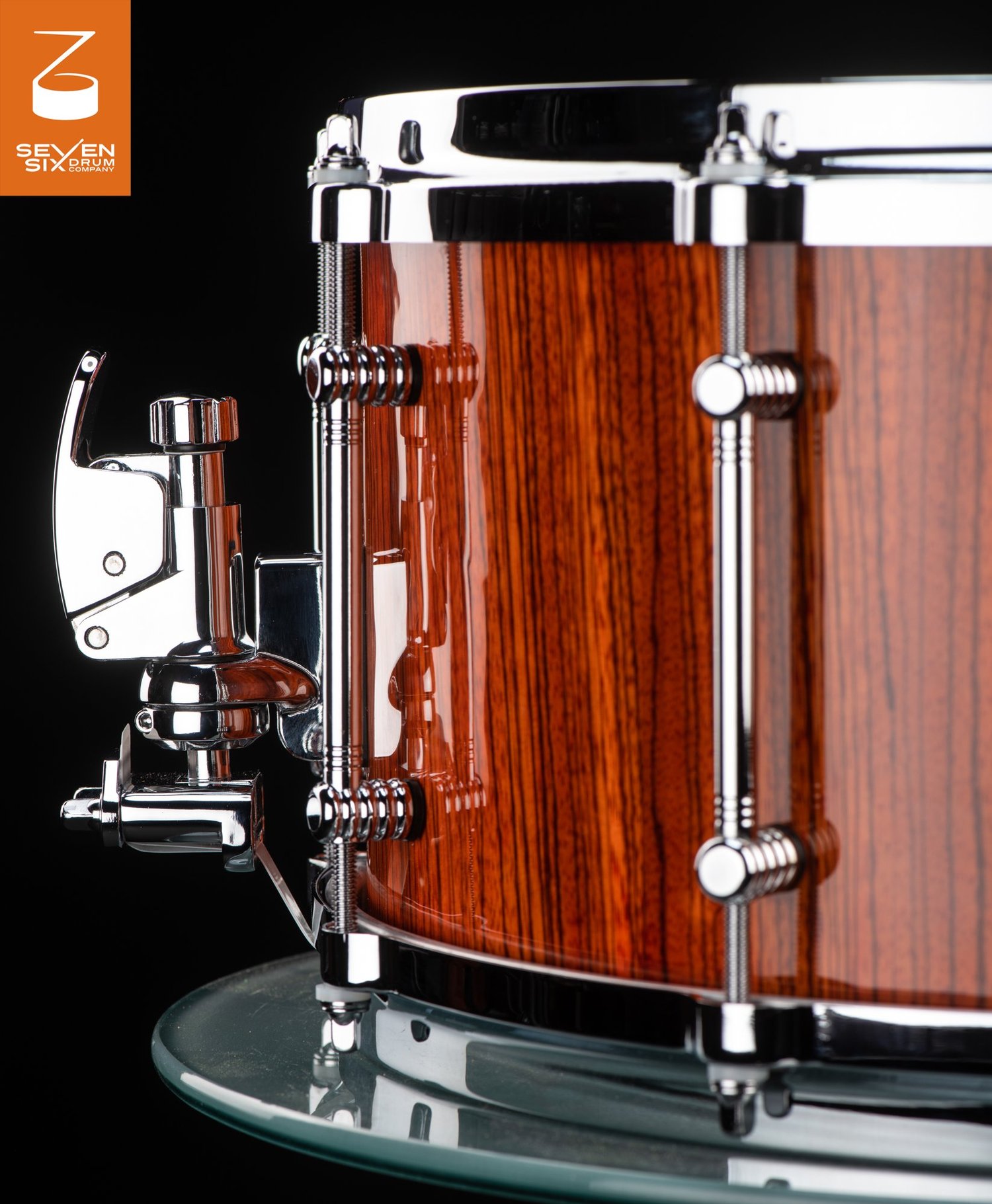 Handmade snare drum with a high-gloss striped wood shell, chrome tube lugs, and a polished snare throw-off.