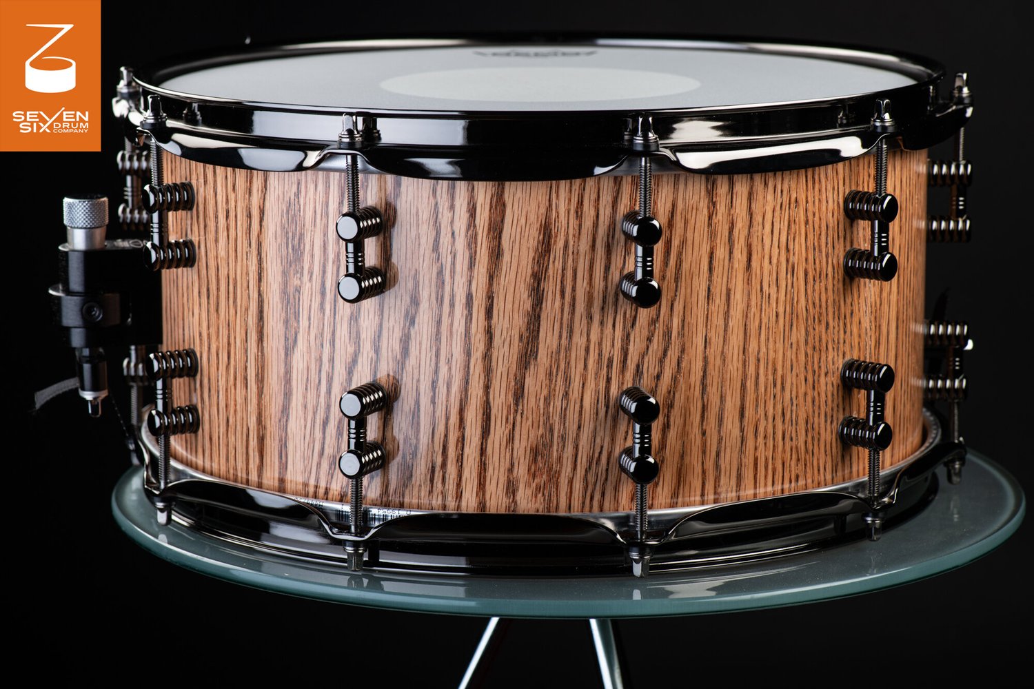 Handmade snare drum with a gloss natural grain wood shell, black nickel hoops, and ribbed dual lugs.