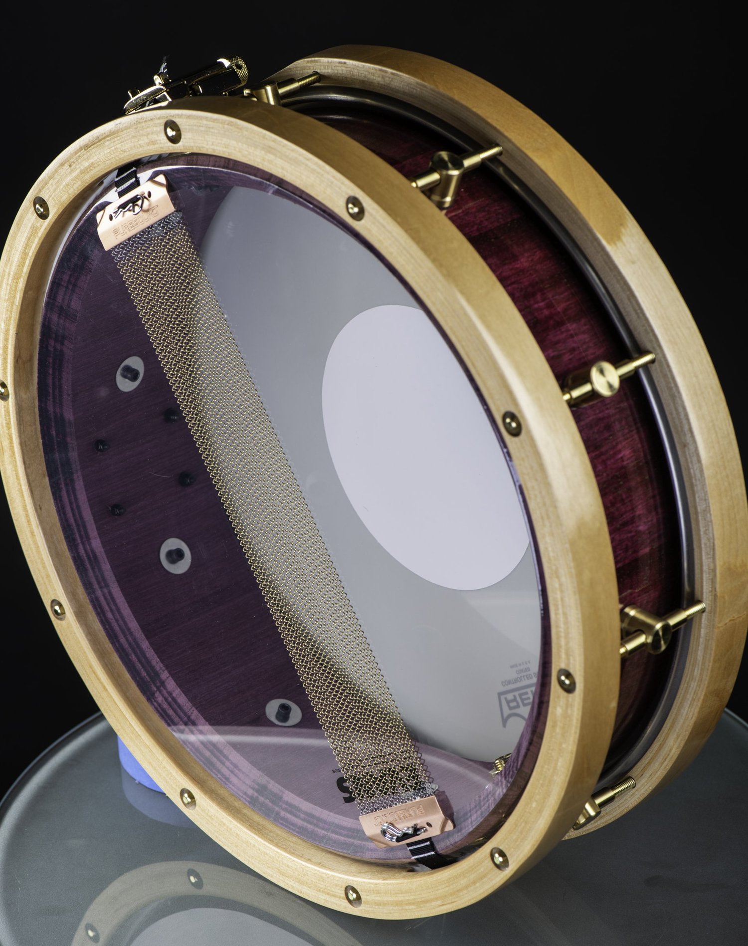 Handmade snare drum with a purple wood shell, natural wood hoops, brass hardware, and bottom snare wires.