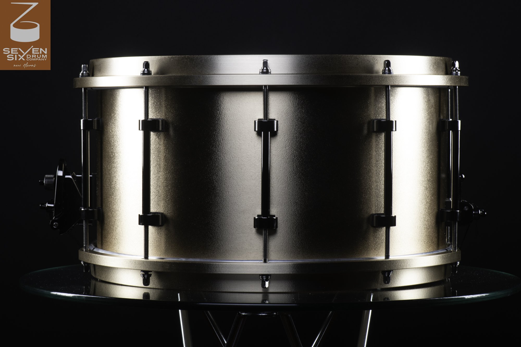 Handmade metal snare drum in a matte bronze finish with matching hoops and black tube lugs.