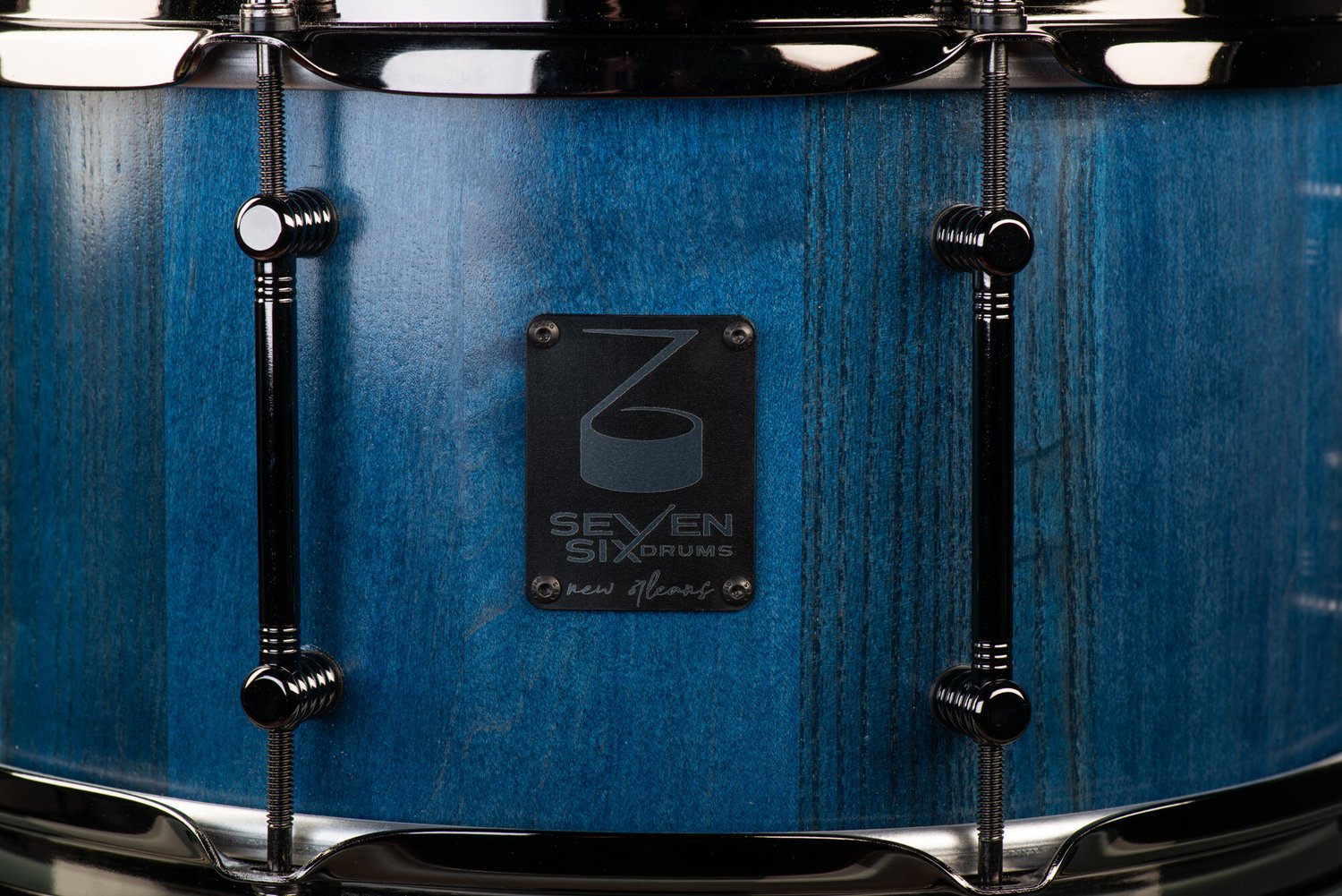 Handmade wood snare drum with a blue stain finish, black nickel tube lugs, and a Seven Six Drums badge.