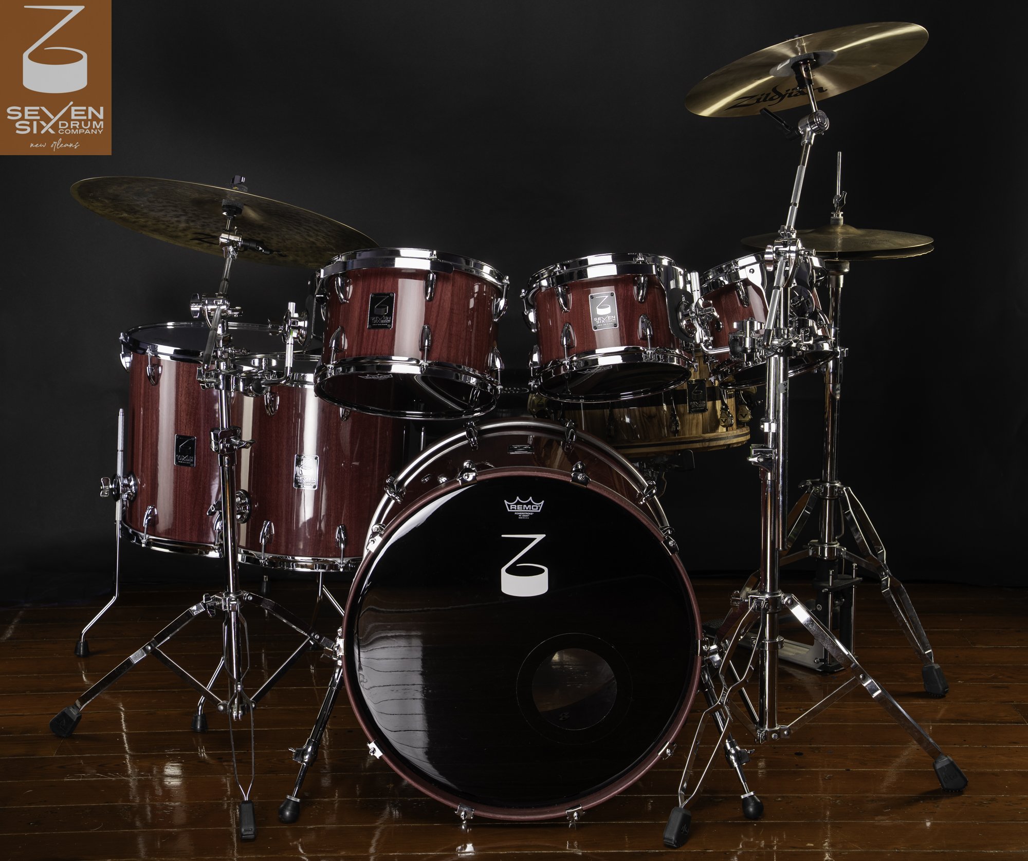 A custom drum kit crafted with gloss purpleheart wood shells, polished chrome hardware, and bronze cymbals.