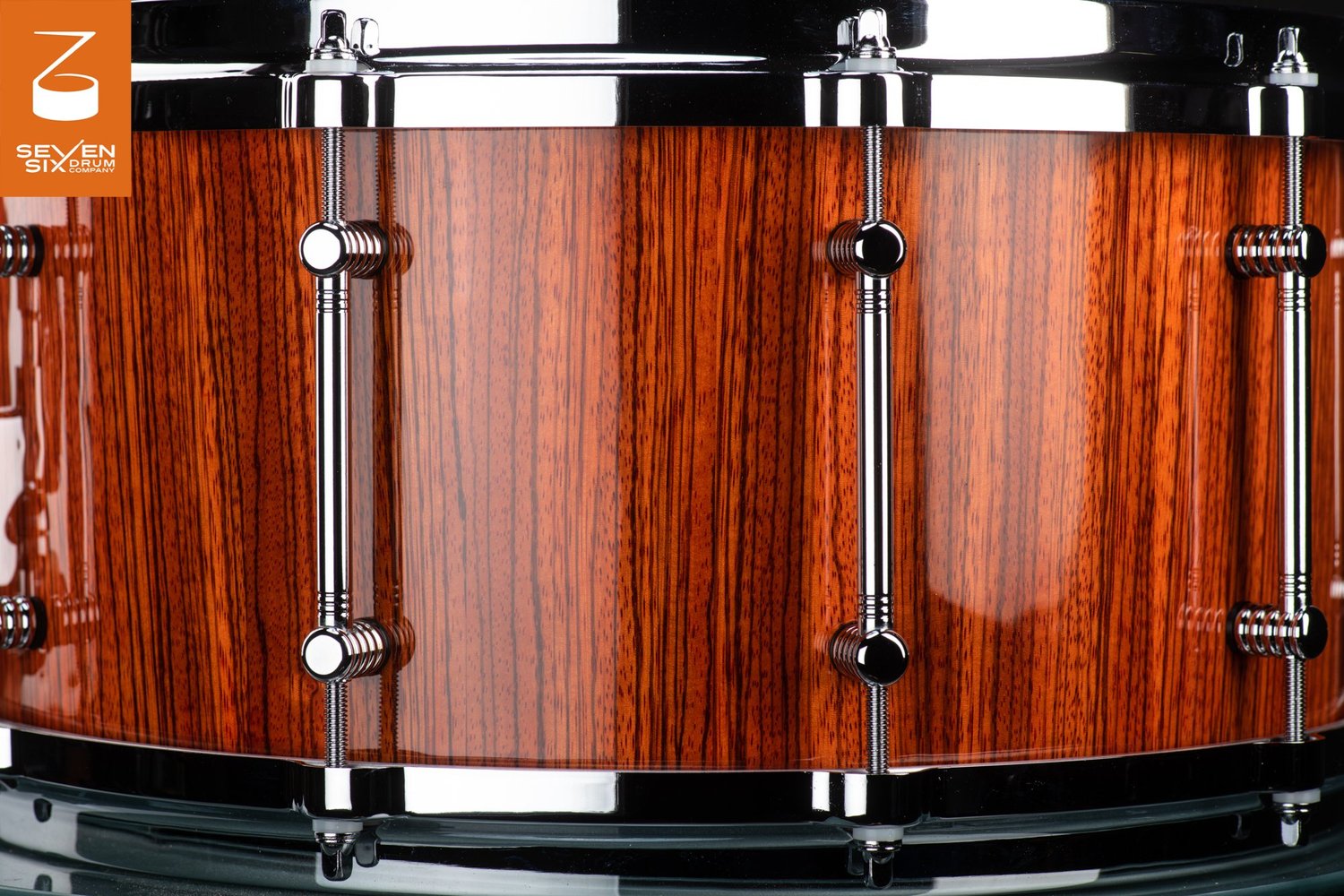 Snare drum shell in a high-gloss vertical wood grain finish, featuring polished chrome tube lugs and hoops.