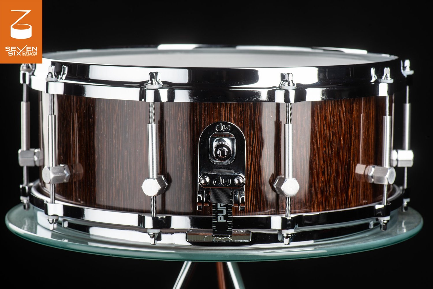 Handmade snare drum with a glossy dark wood shell, chrome hoops, hex lugs, and a DW butt plate.
