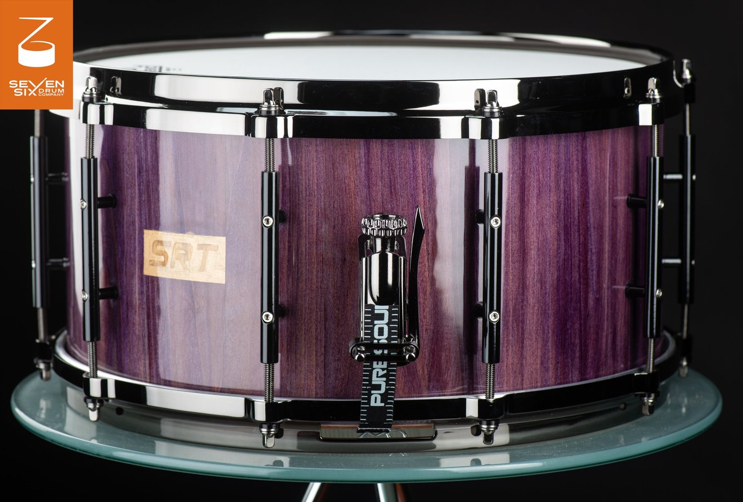 Handmade snare drum with a gloss purple wood shell, black tube lugs, and a chrome snare throw-off.
