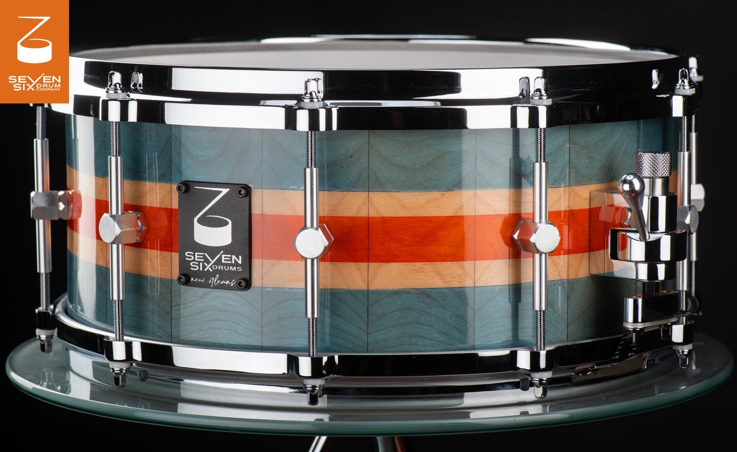 Handmade wood snare drum featuring a glossy teal, natural, and orange finish with chrome hoops and a side throw-off.