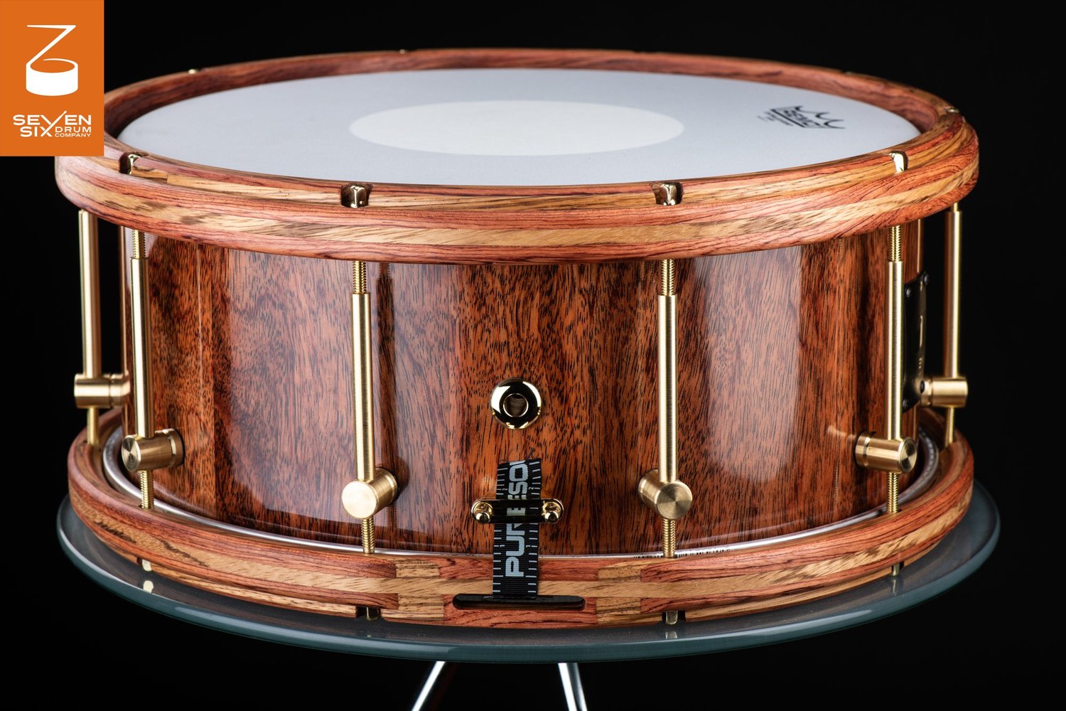 Glossy natural wood snare drum featuring matching segmented wood hoops and brass tube lugs.