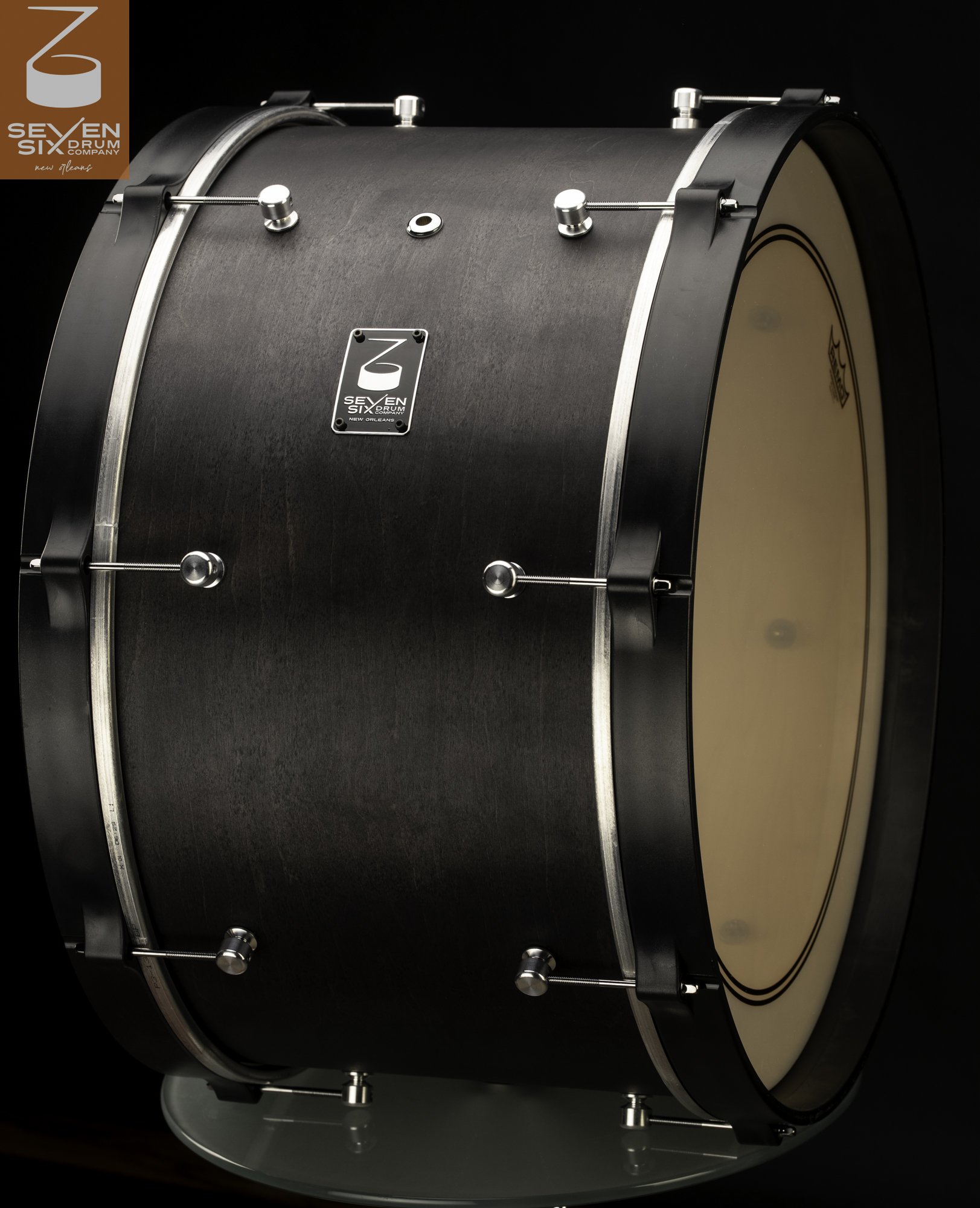 Matte black wood bass drum with brushed silver accent bands, black hoops, and round chrome tension lugs.
