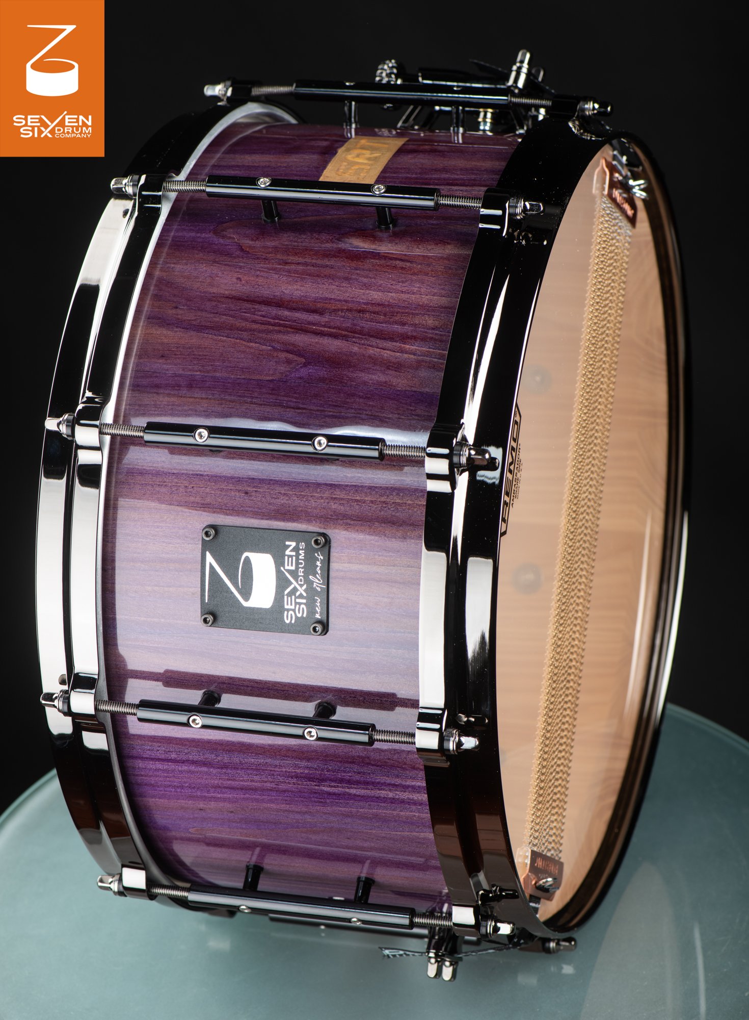 Deep wooden snare drum featuring a glossy purple wood finish with black nickel hoops and tube lugs.