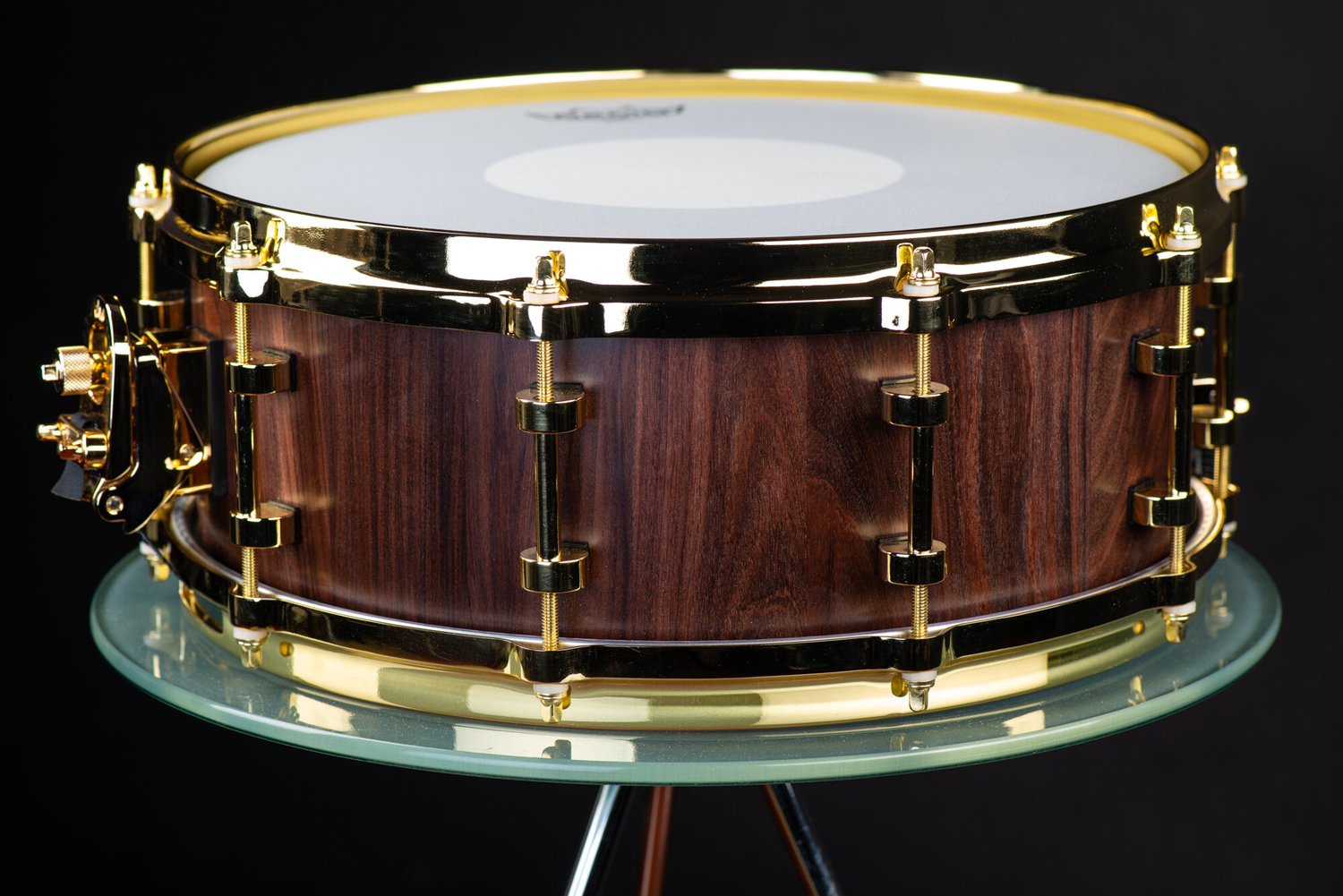 Handmade snare drum featuring a dark walnut shell with a natural satin finish and polished gold hardware.