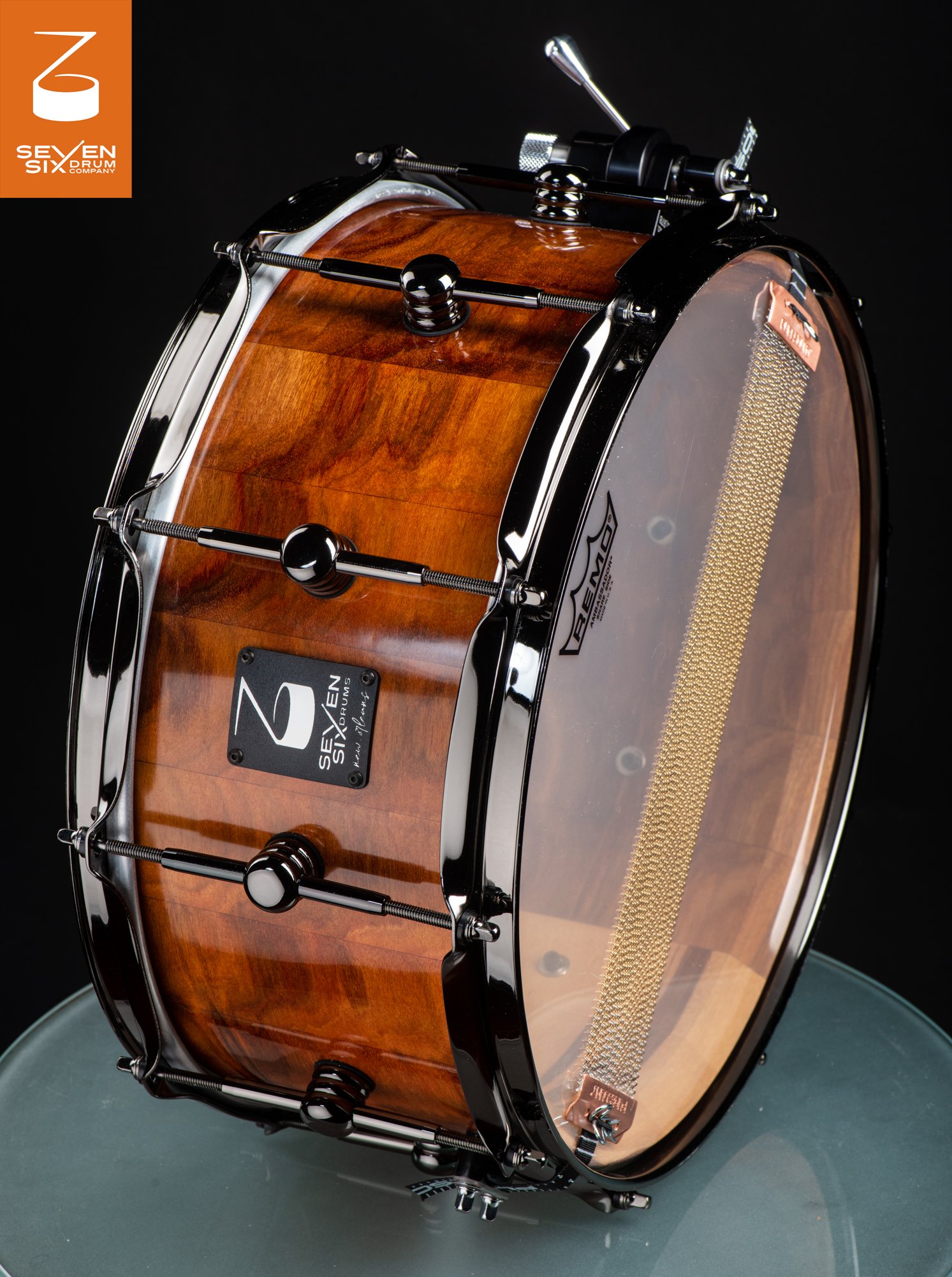 Handmade snare drum with a high-gloss natural wood shell, black nickel hoops and lugs, and brass snare wires.