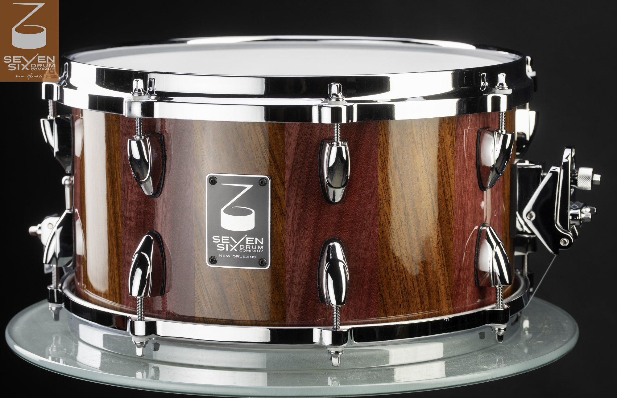 Handmade snare drum made of high-gloss striped purple and brown wood with chrome hoops and teardrop lugs.