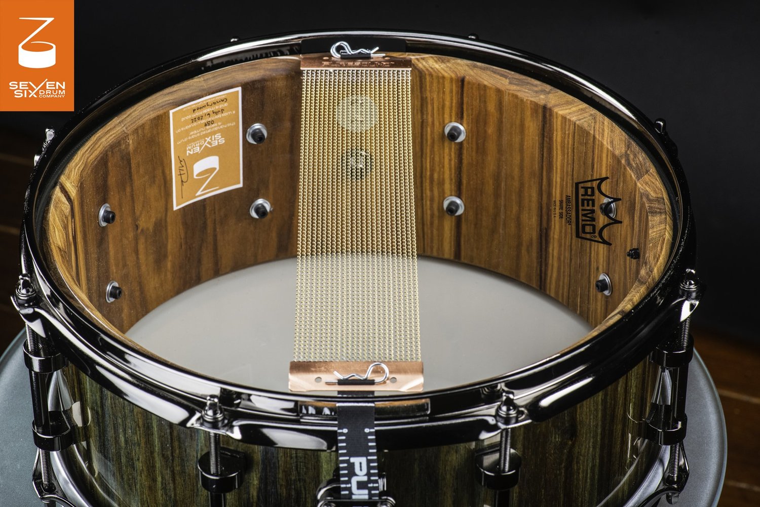 Bottom view of a solid canarywood snare drum with black chrome hoops and PureSound brass snare wires.