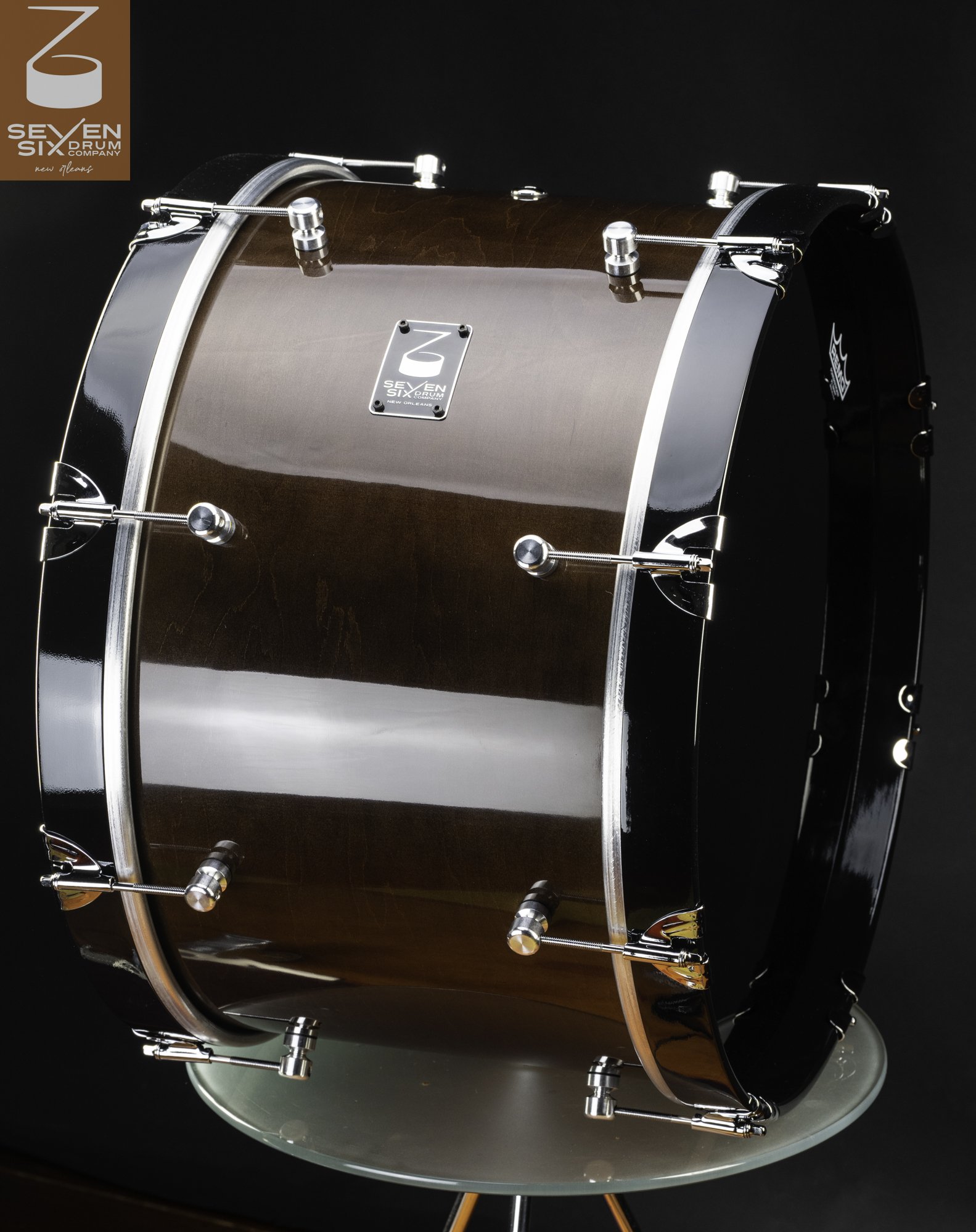 Glossy brown wood bass drum with chrome claw hooks, round lugs, and gloss black hoops.