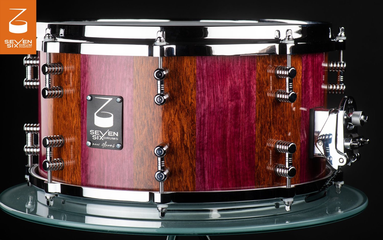 Stave snare drum in glossy alternating purpleheart and Jatoba wood, featuring chrome diecast hoops, lugs, and throw-off.