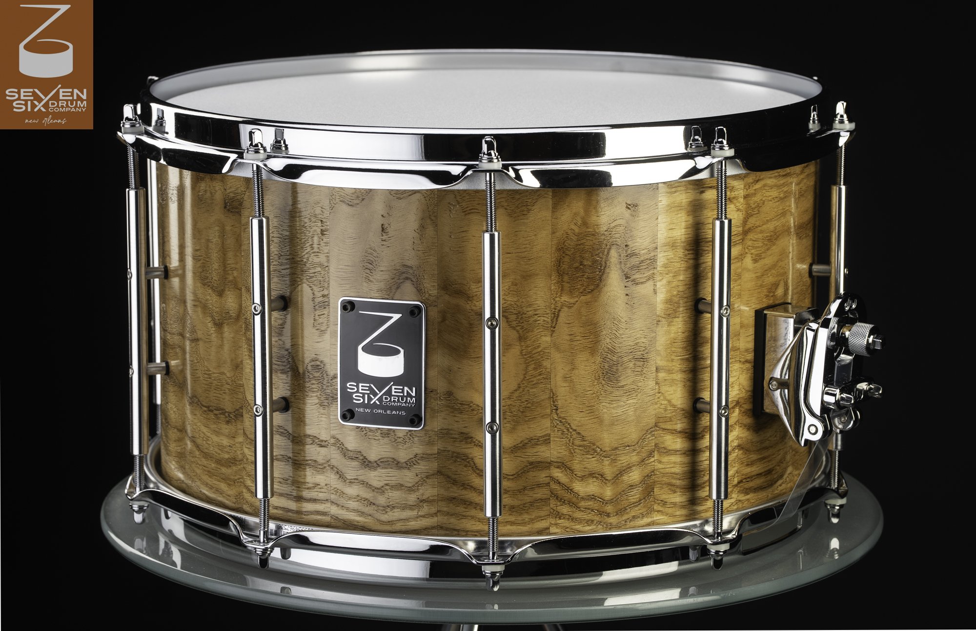 Handmade snare drum featuring a glossy natural stave wood shell, chrome tube lugs, and polished hoops.