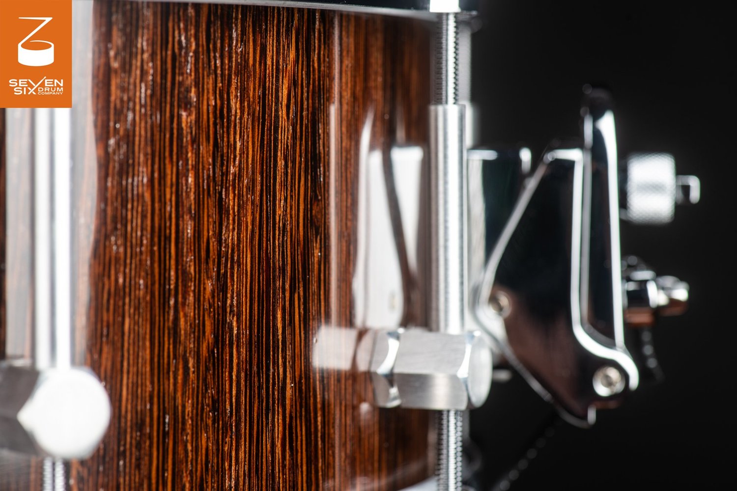 Glossy dark wood snare drum featuring chrome tension rod hardware and a side throw-off strainer.