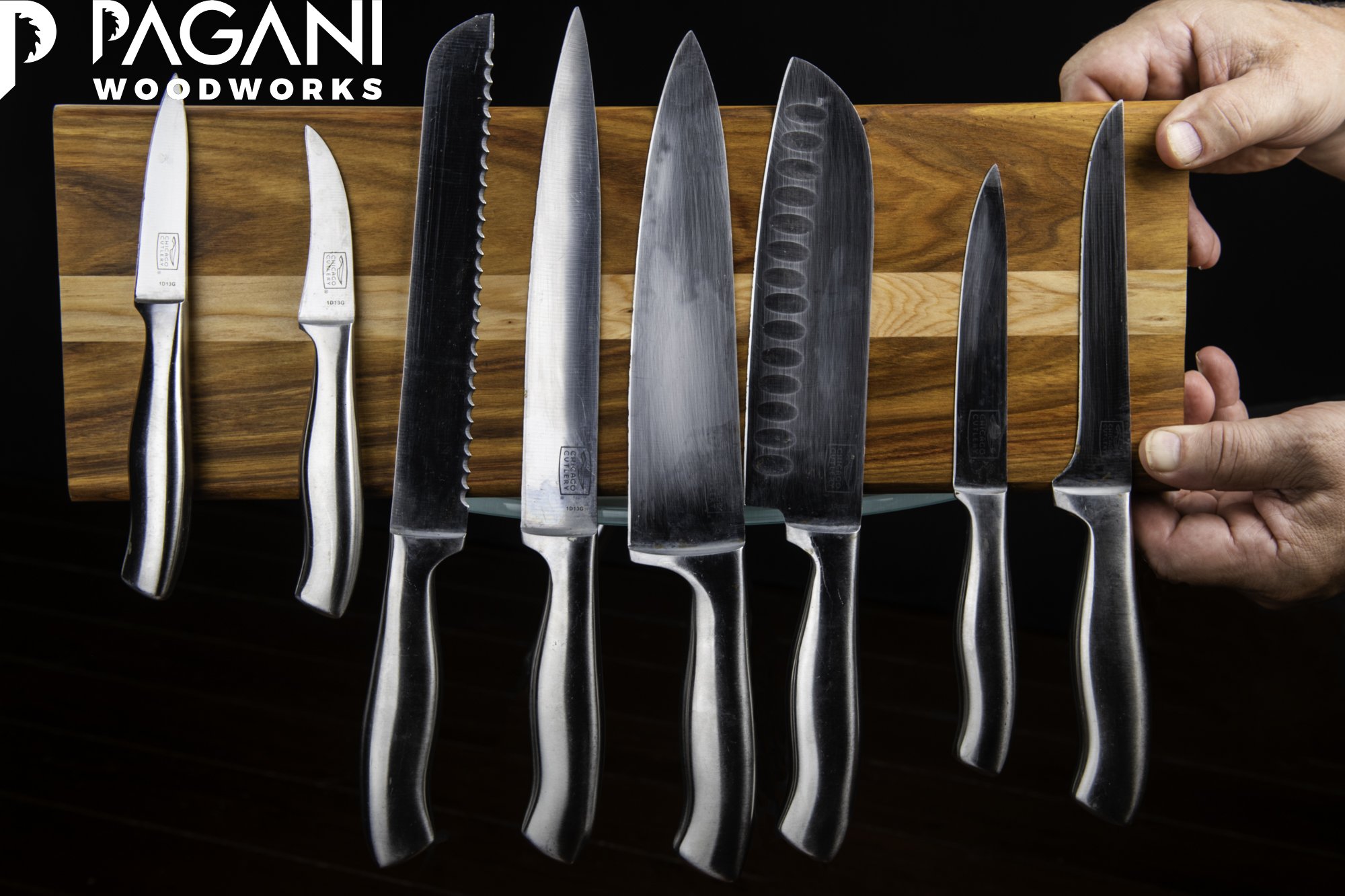 A two-tone hardwood magnetic knife rack with a natural finish, holding seven stainless steel kitchen knives.