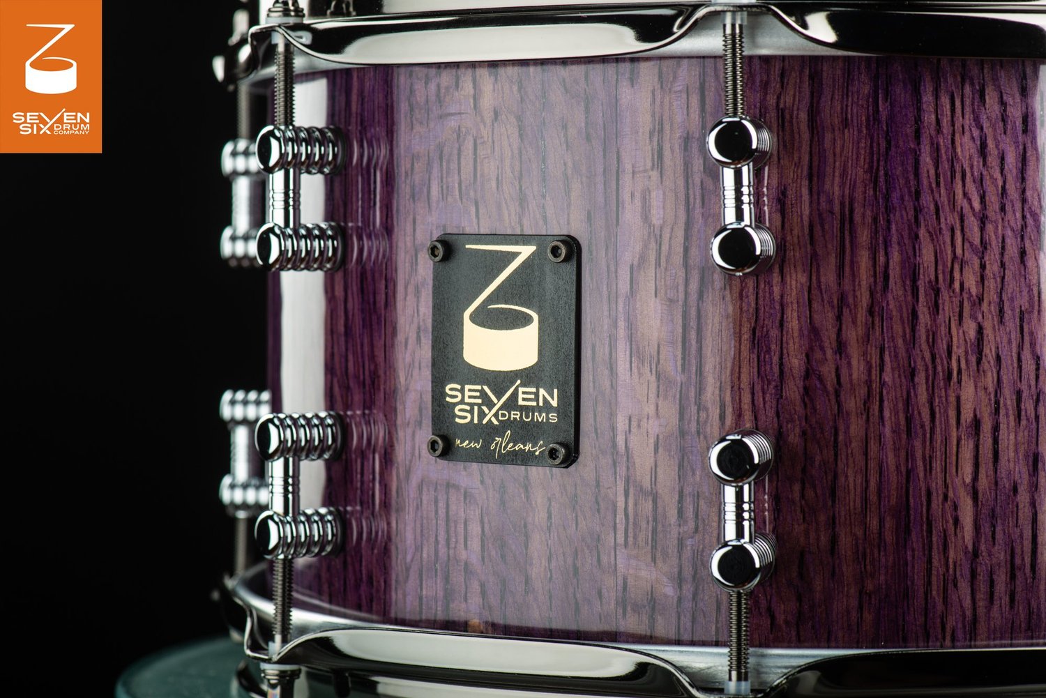 Handmade snare drum featuring a glossy purple wood grain shell, polished chrome lugs, and a black Seven Six Drums badge.