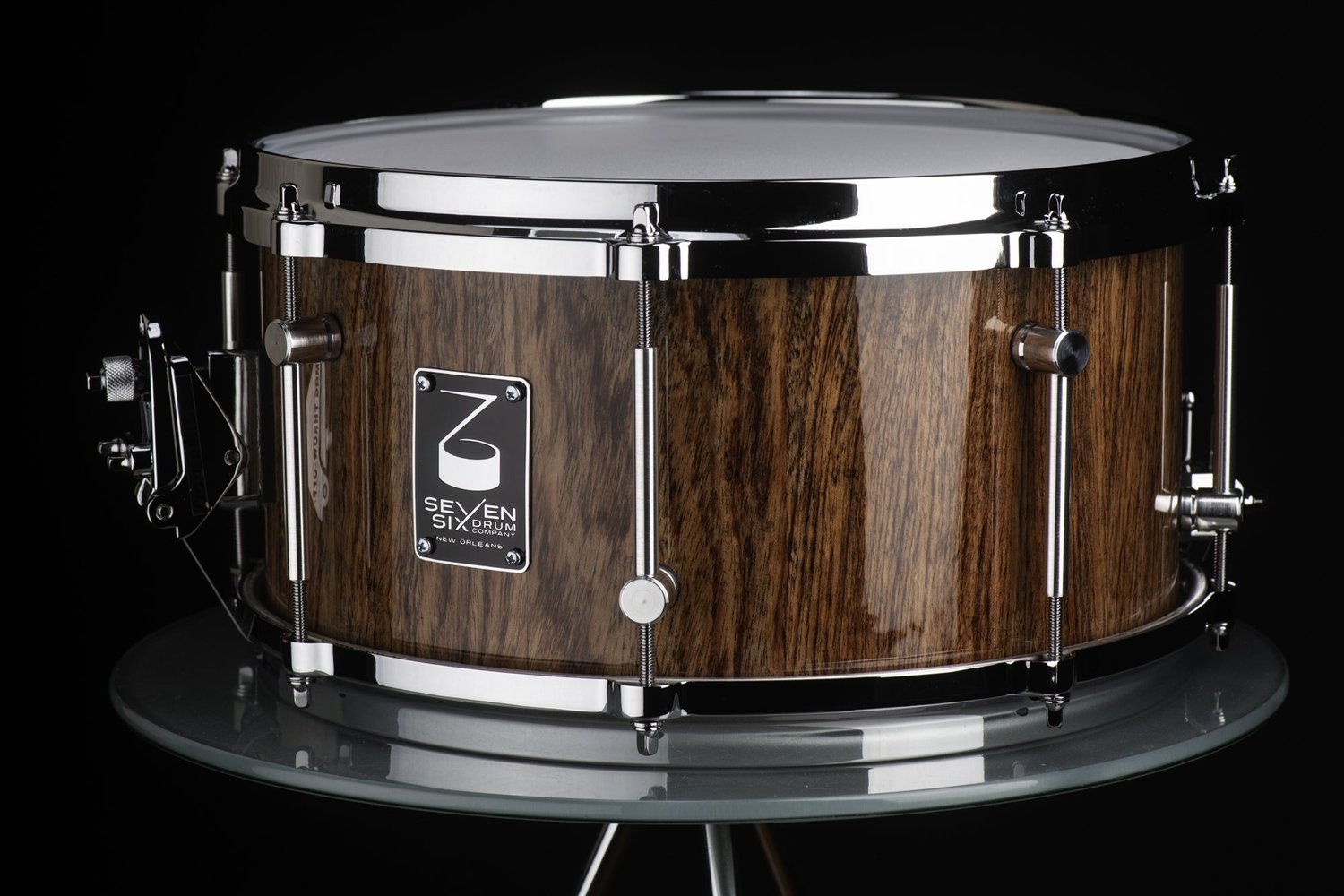 Handmade Bubinga snare drum with a glossy natural wood finish, polished die-cast chrome hoops, and sleek tube lugs.