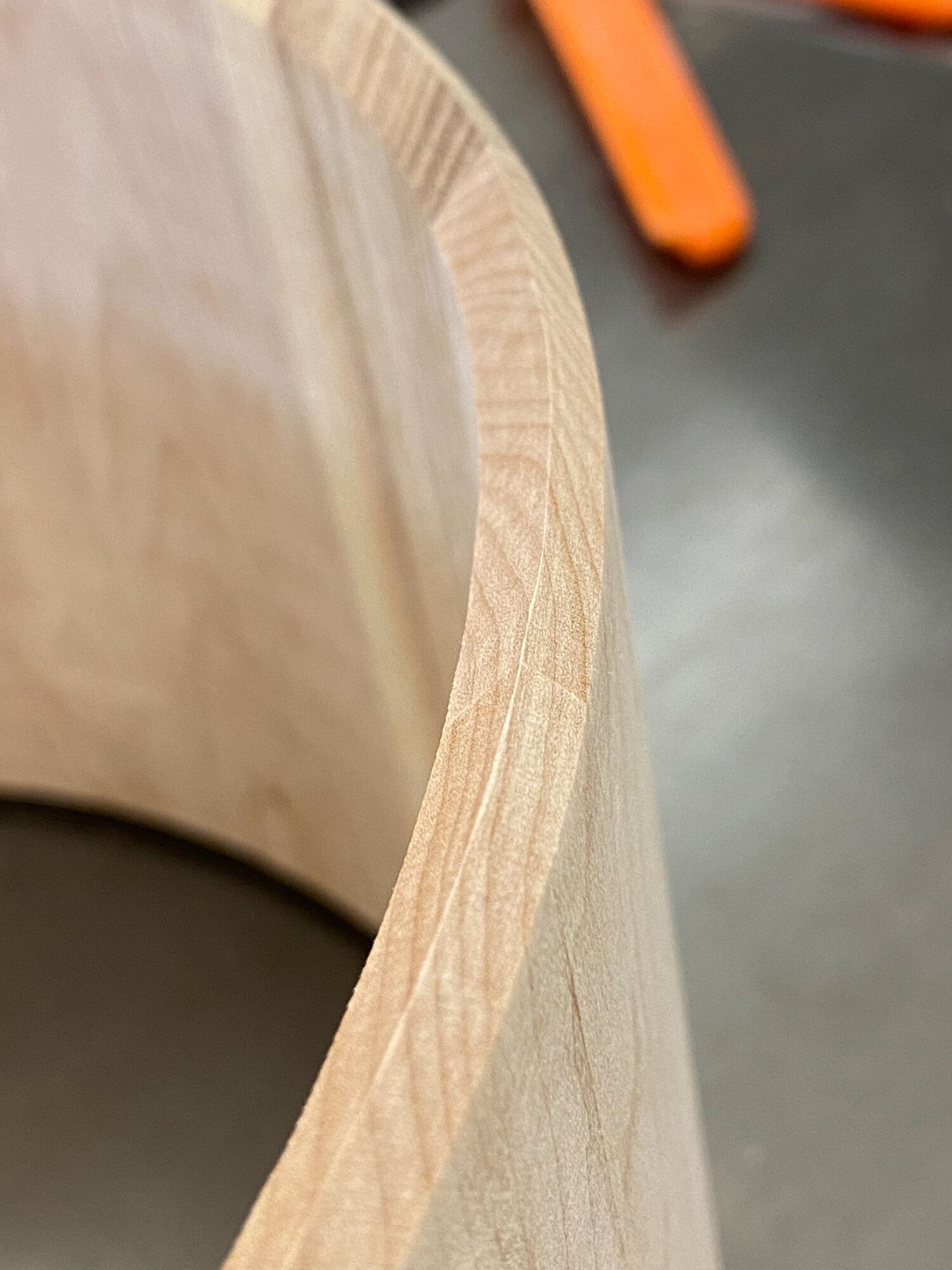 Close-up of the cut bearing edge on an unfinished light wood snare drum shell with no hardware installed.