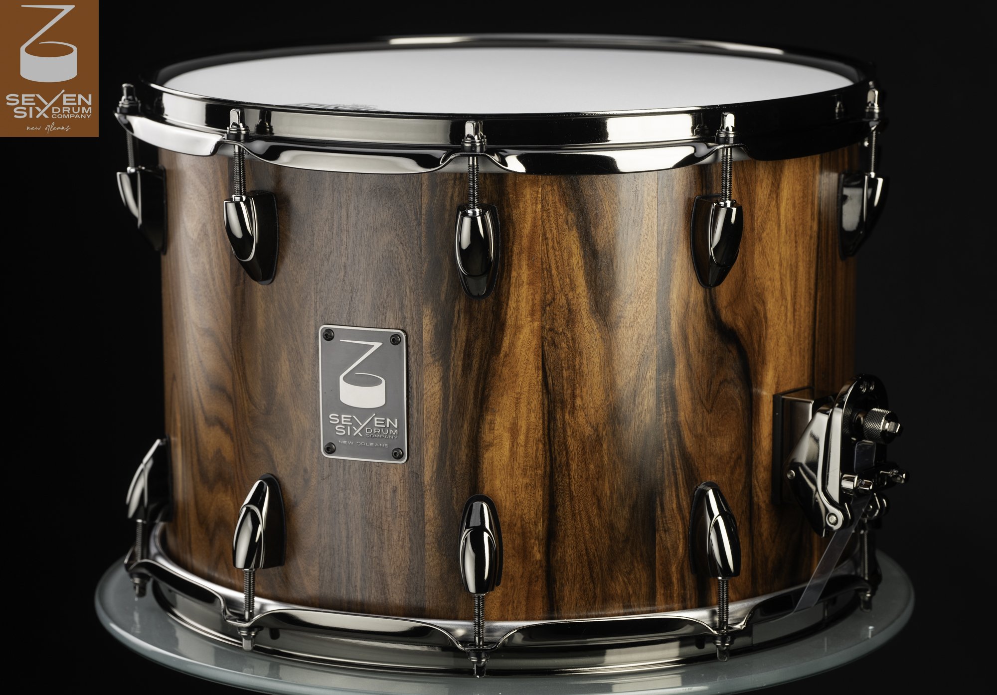 Handcrafted snare drum featuring a vertical-grain natural wood shell with polished black nickel hoops and lugs.