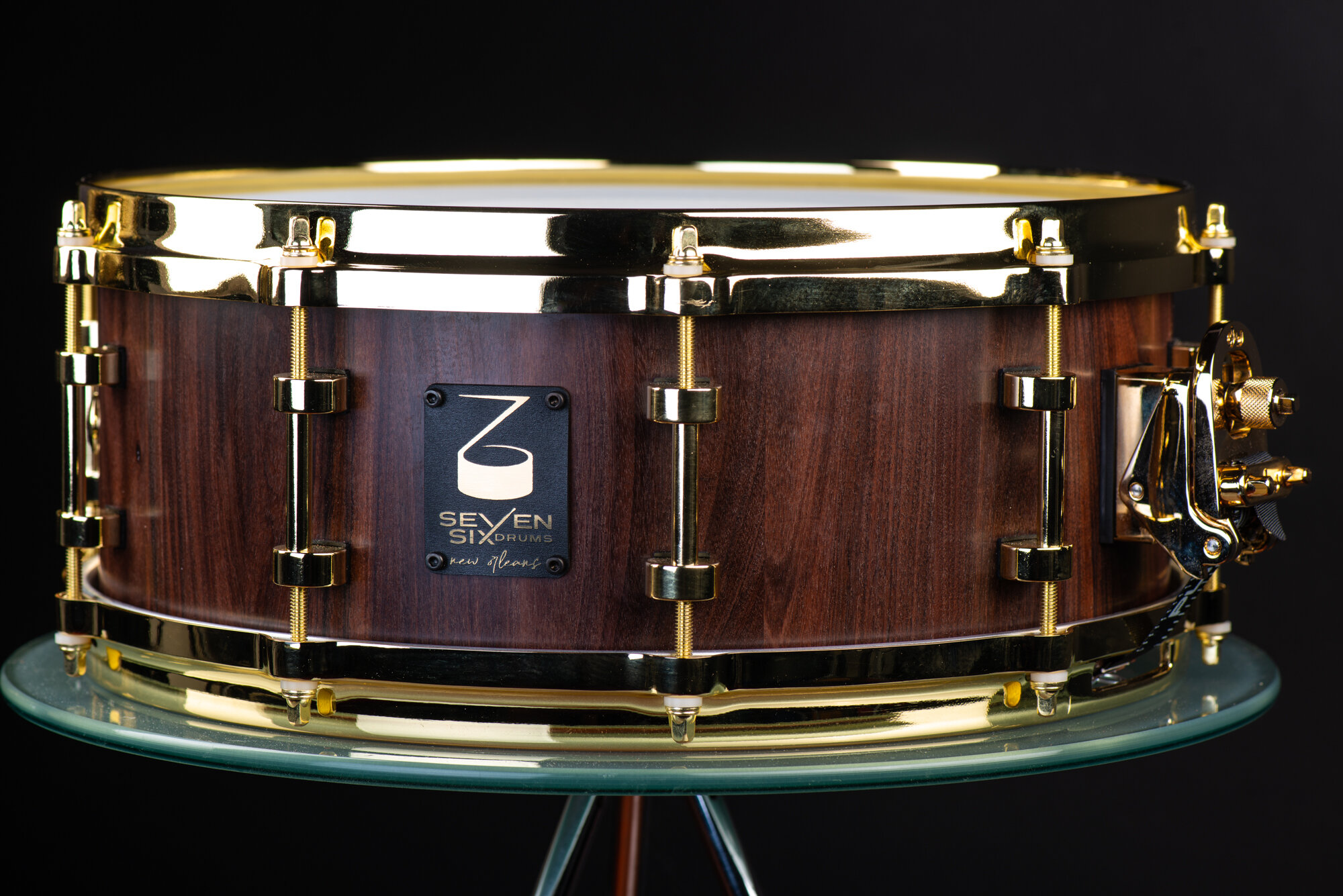 Handmade snare drum with a satin dark walnut shell, polished gold hoops, lugs, and a snare throw-off.
