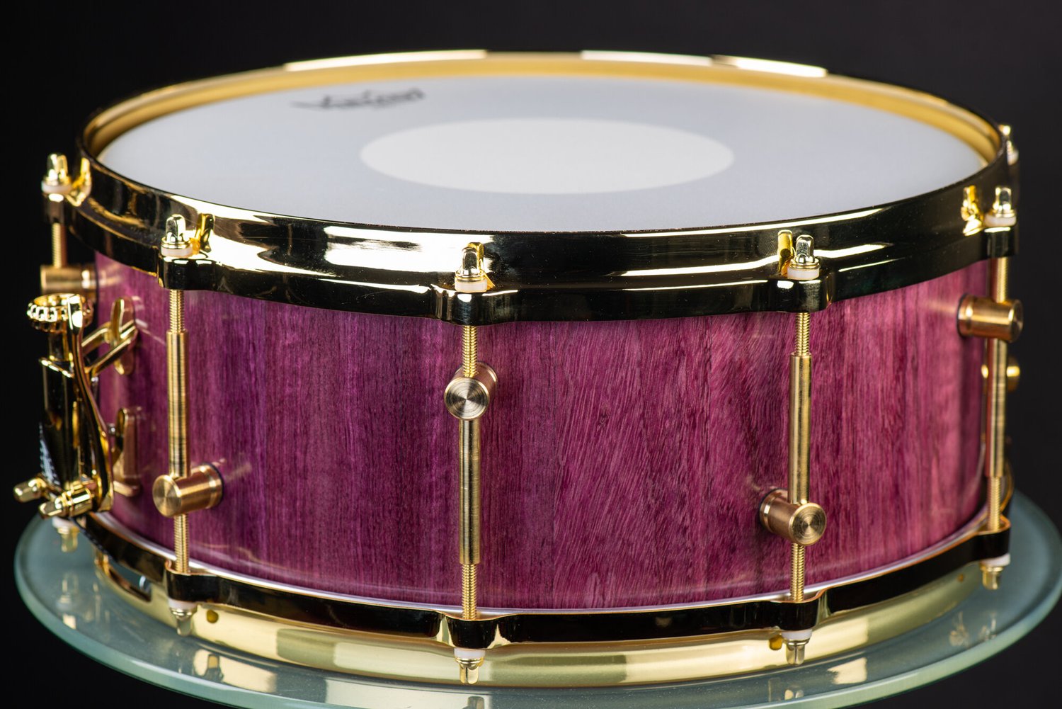Handmade snare drum with a purpleheart wood shell, natural finish, and polished brass tube lugs and hoops.