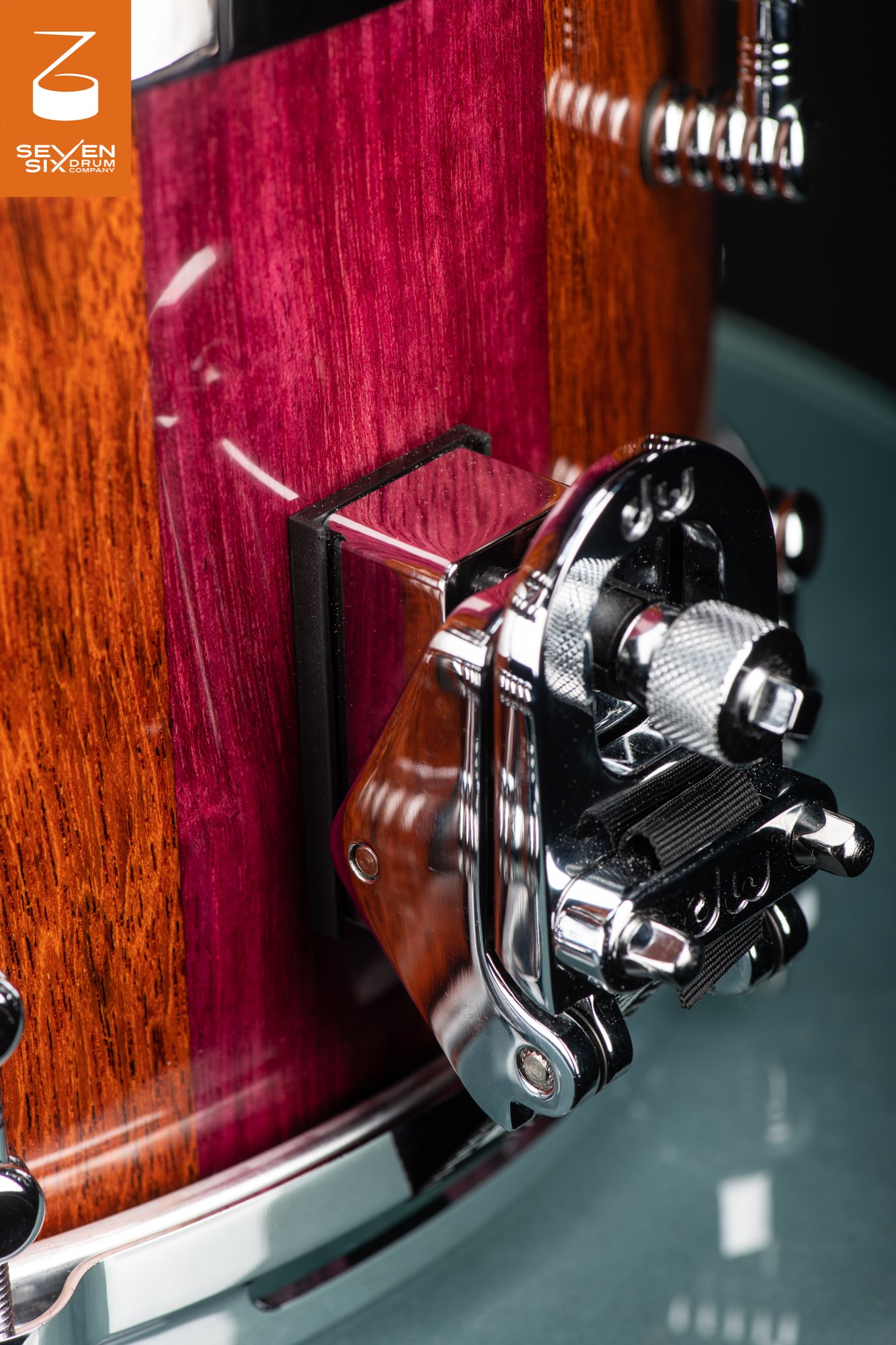 A glossy purpleheart and natural wood snare drum shell fitted with a chrome DW throw-off mechanism.