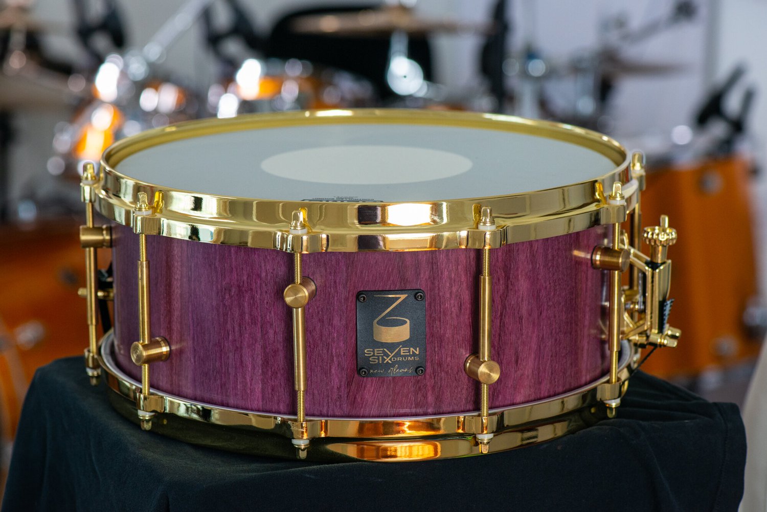 Handmade snare drum featuring a purpleheart wood shell, polished gold hoops, and brass tube lugs.