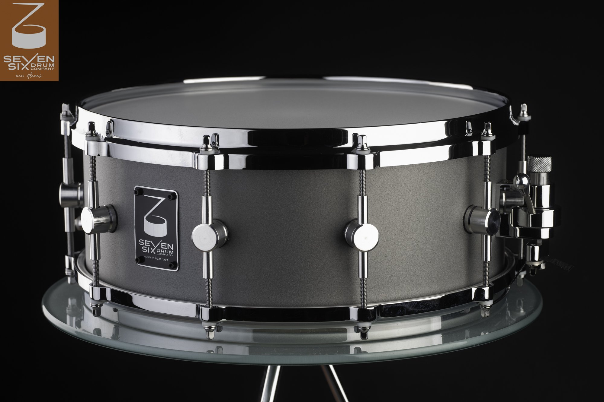 Matte gray metal snare drum featuring polished chrome hoops, sleek center-mount lugs, and a side-mounted throw-off.