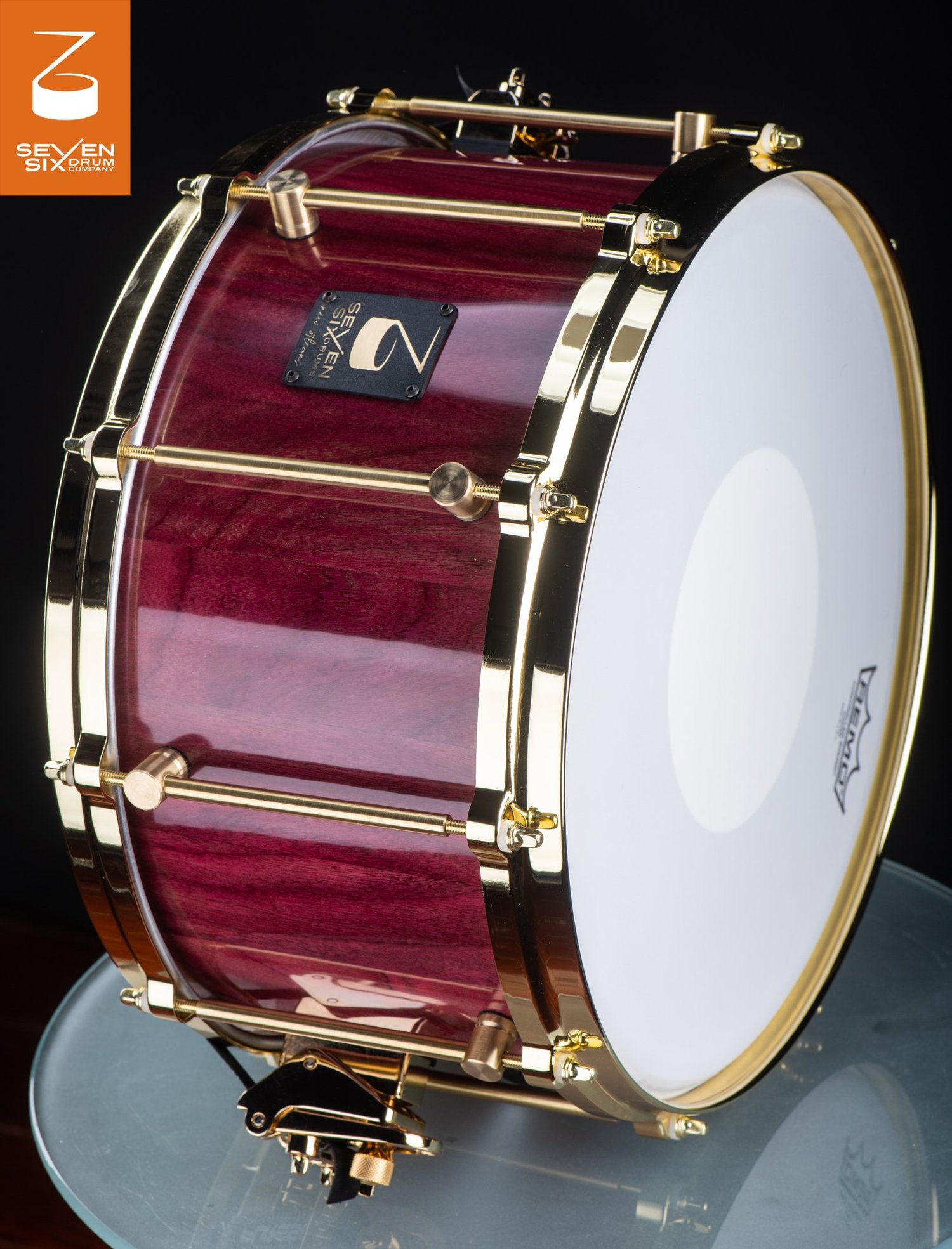 Deep handmade snare drum featuring a glossy purpleheart wood shell with polished brass hoops and lugs.