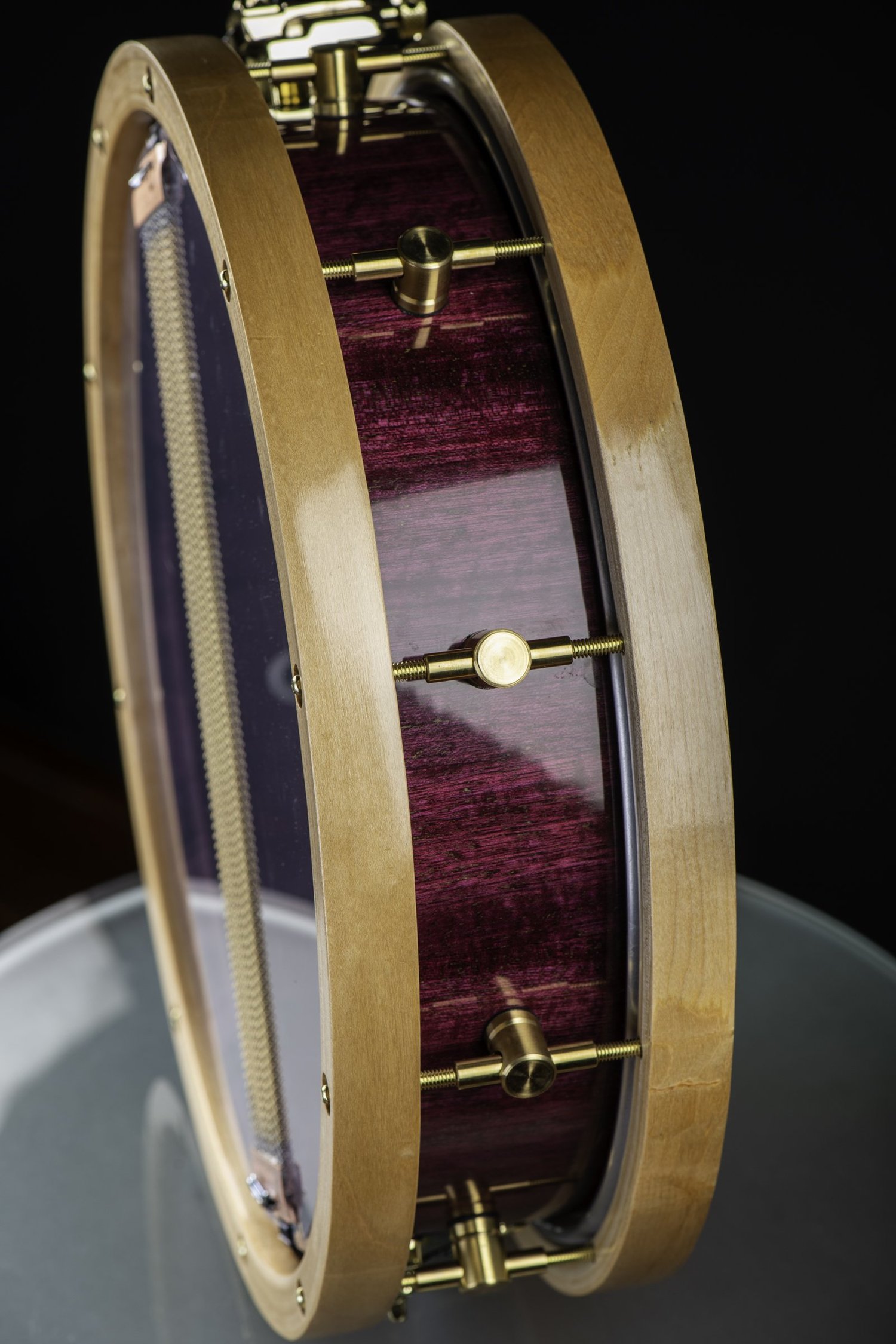 Handmade snare drum featuring a high-gloss purple shell, natural wood hoops, and brass lugs.