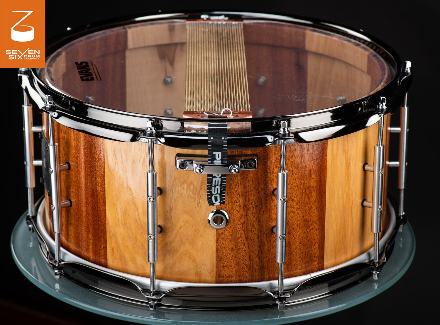 Handmade stave snare drum featuring alternating natural wood staves, black nickel hoops, and chrome tube lugs.