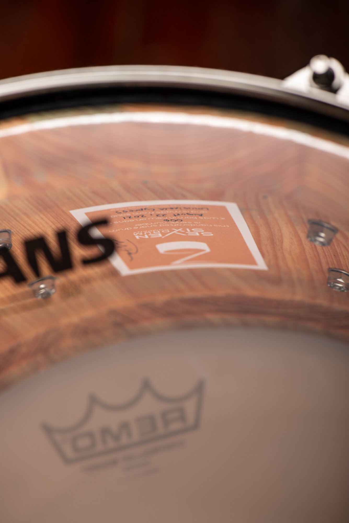Natural solid cypress snare drum shell viewed through a clear drumhead, featuring a chrome hoop and interior lug screws.