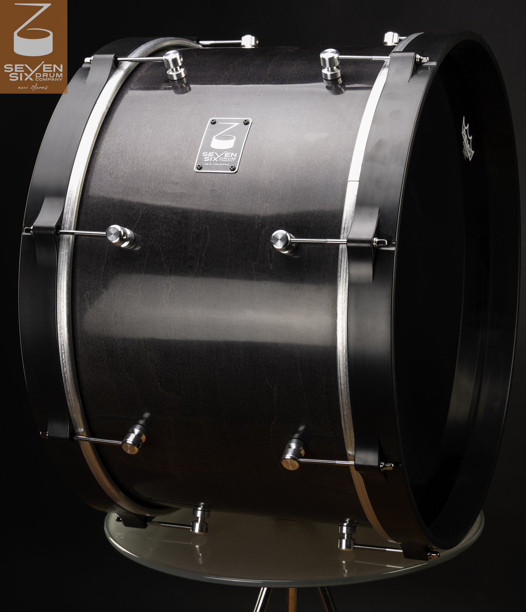 Dark-stained wood bass drum with a satin finish, round chrome lugs, and wide black wood hoops.