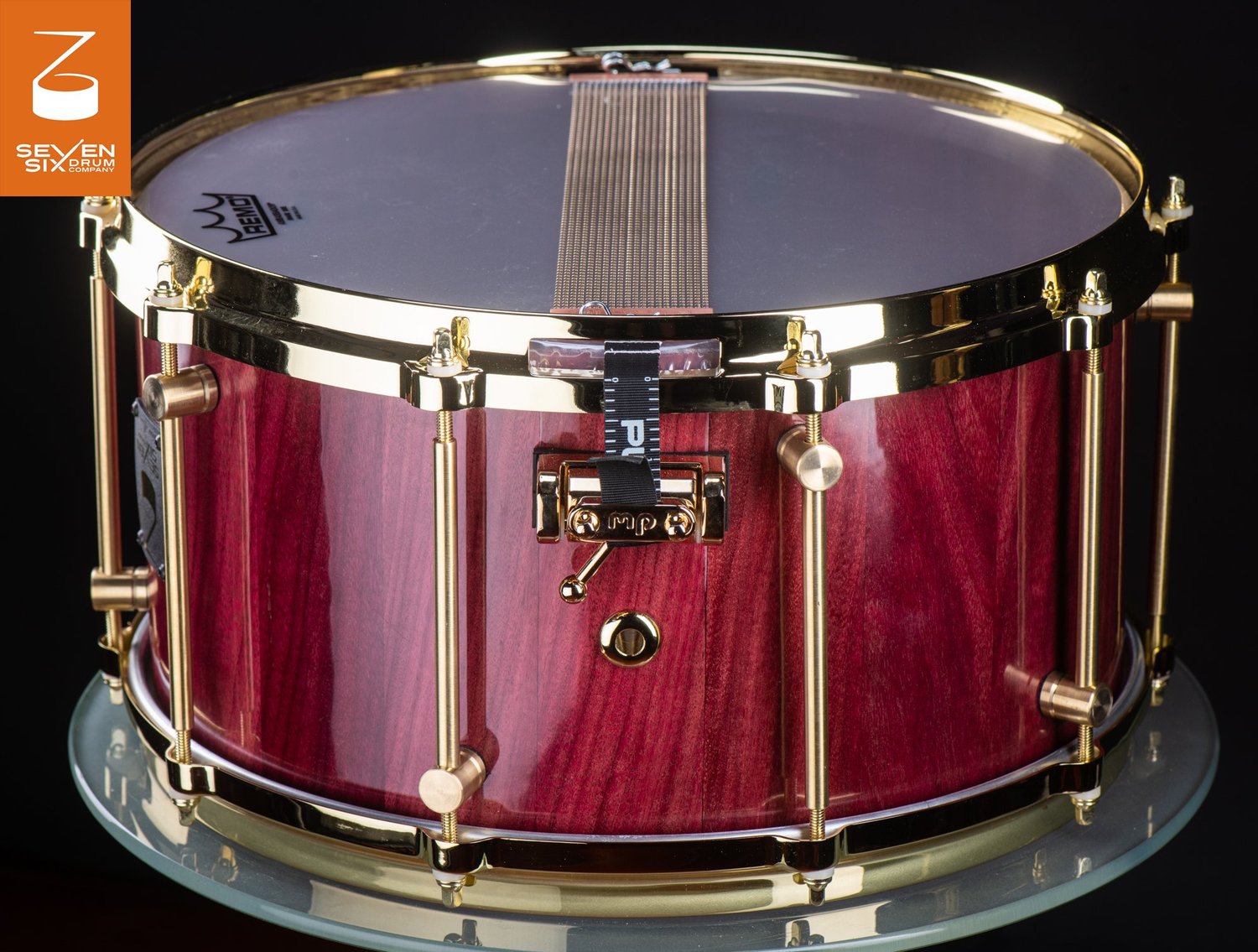 Handmade snare drum crafted from glossy purpleheart wood with polished brass tube lugs and hoops.