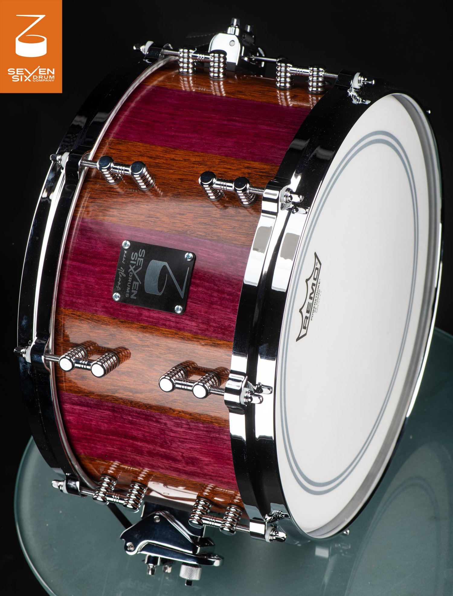 Handmade snare drum featuring a glossy purpleheart and brown wood striped shell with polished chrome hoops and lugs.