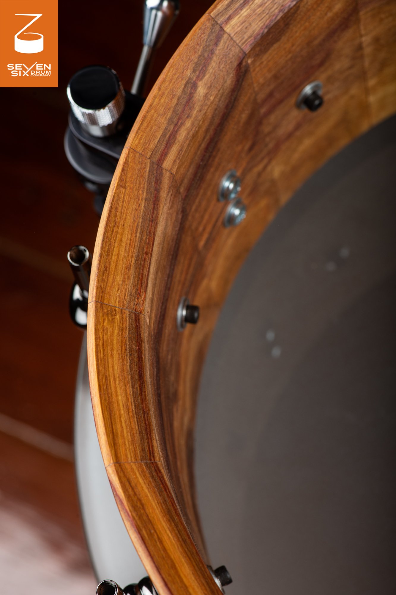 Interior of a natural wood stave snare drum shell showing the beveled bearing edge and mounted chrome and black throw-off.