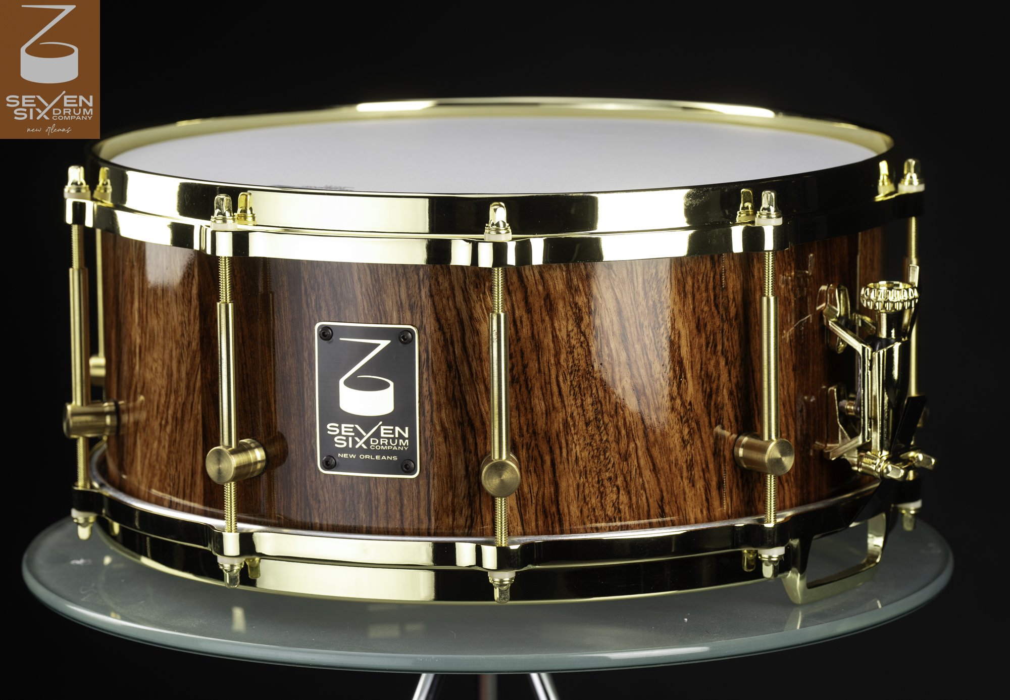 Handmade snare drum featuring a glossy natural wood shell with polished brass hoops and lugs.