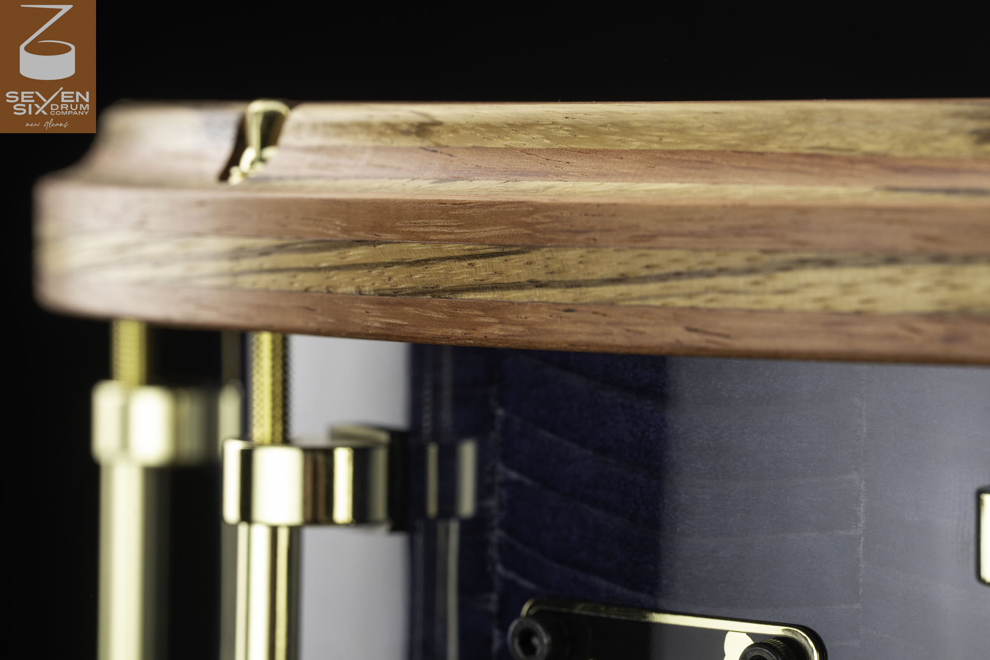 Snare drum featuring a laminated hardwood hoop, blue-stained wood shell, and polished brass hardware.